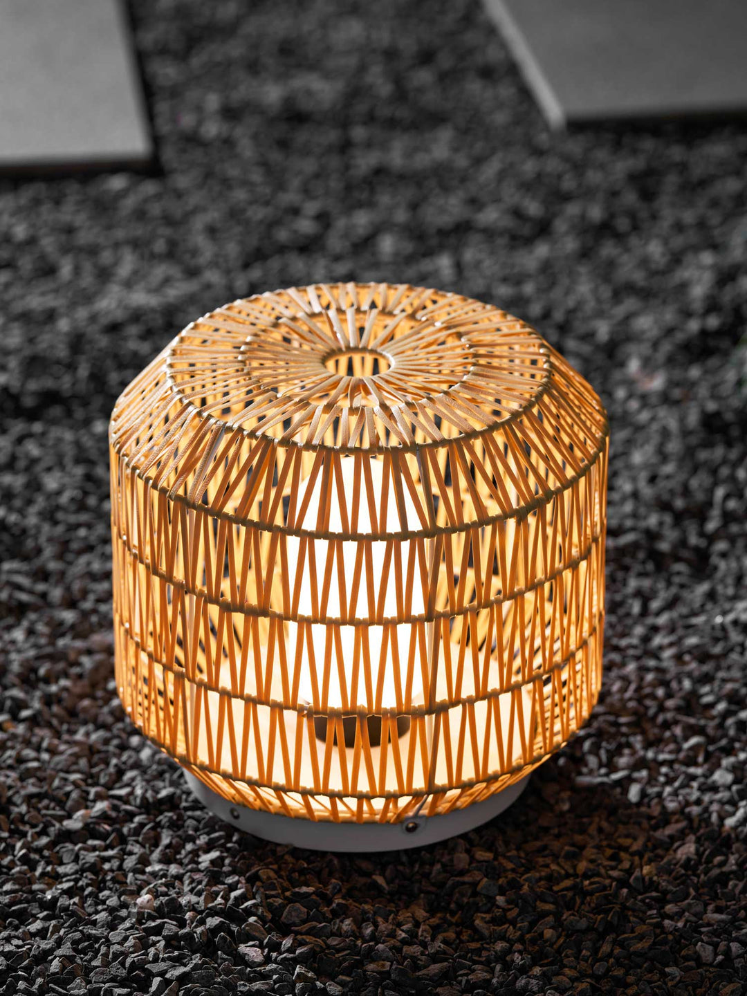 The woven rattan outdoor lamp in a garden environment.
