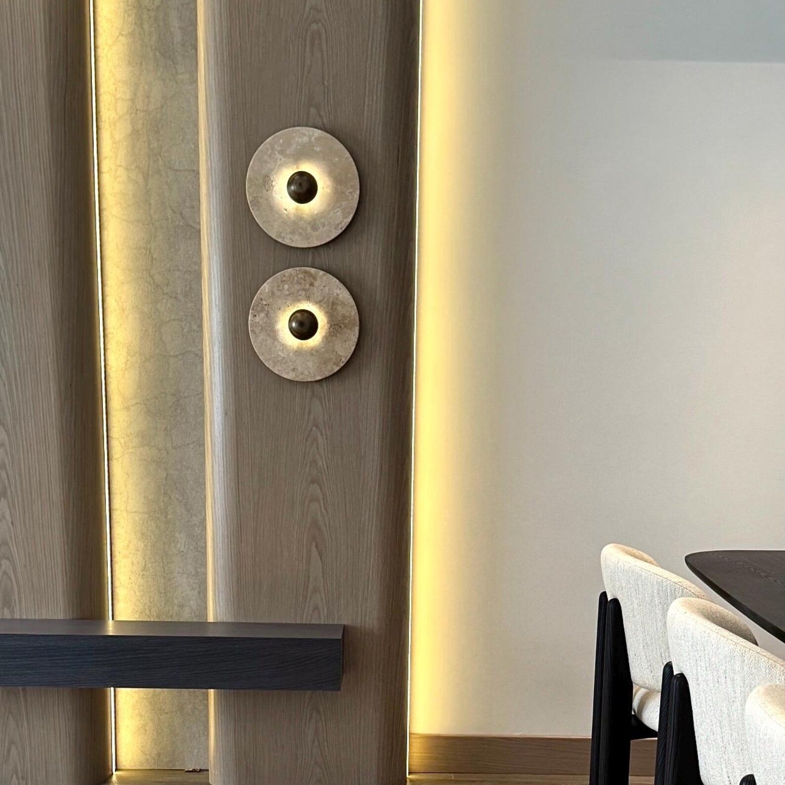 Angled view of the Alese Travertine Wall Lamp highlighting its circular design.