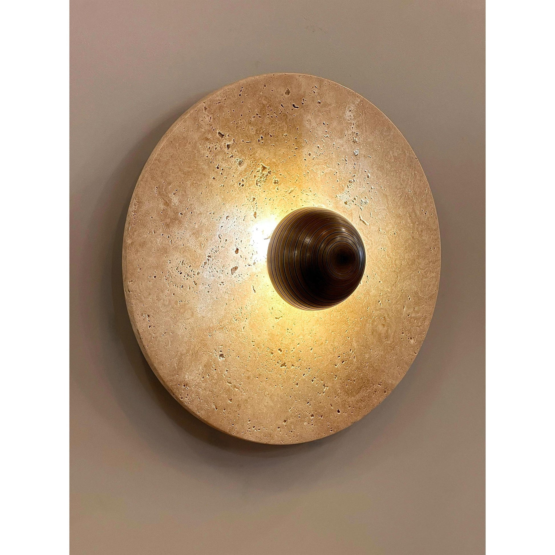 Side profile of the Alese Travertine Wall Lamp, showing its depth and metal shade.