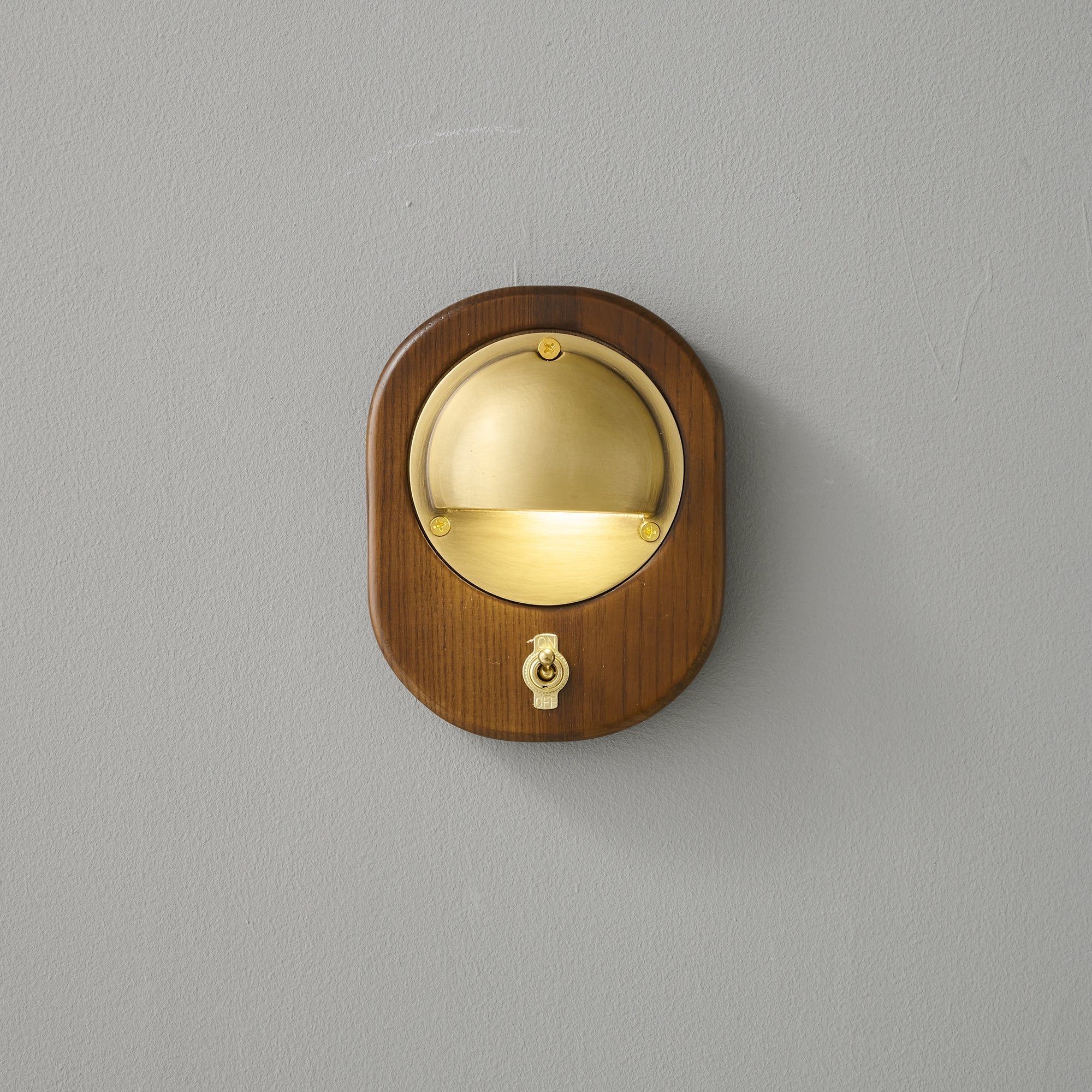 Alfi Wall Lamp, Brass finish, against a dark wall.