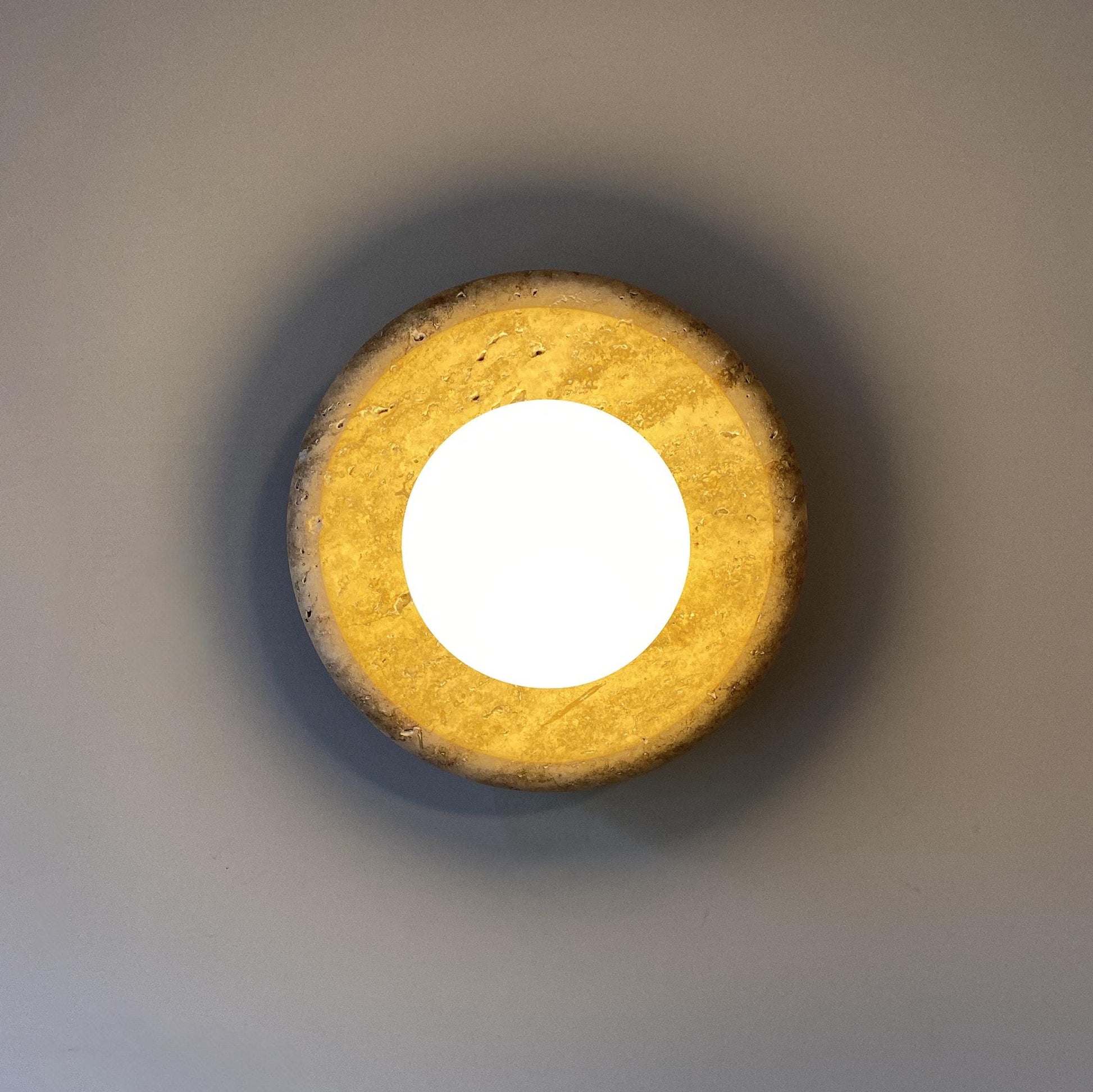 Lifestyle image showing the travertine wall lamp installed in a modern living room.