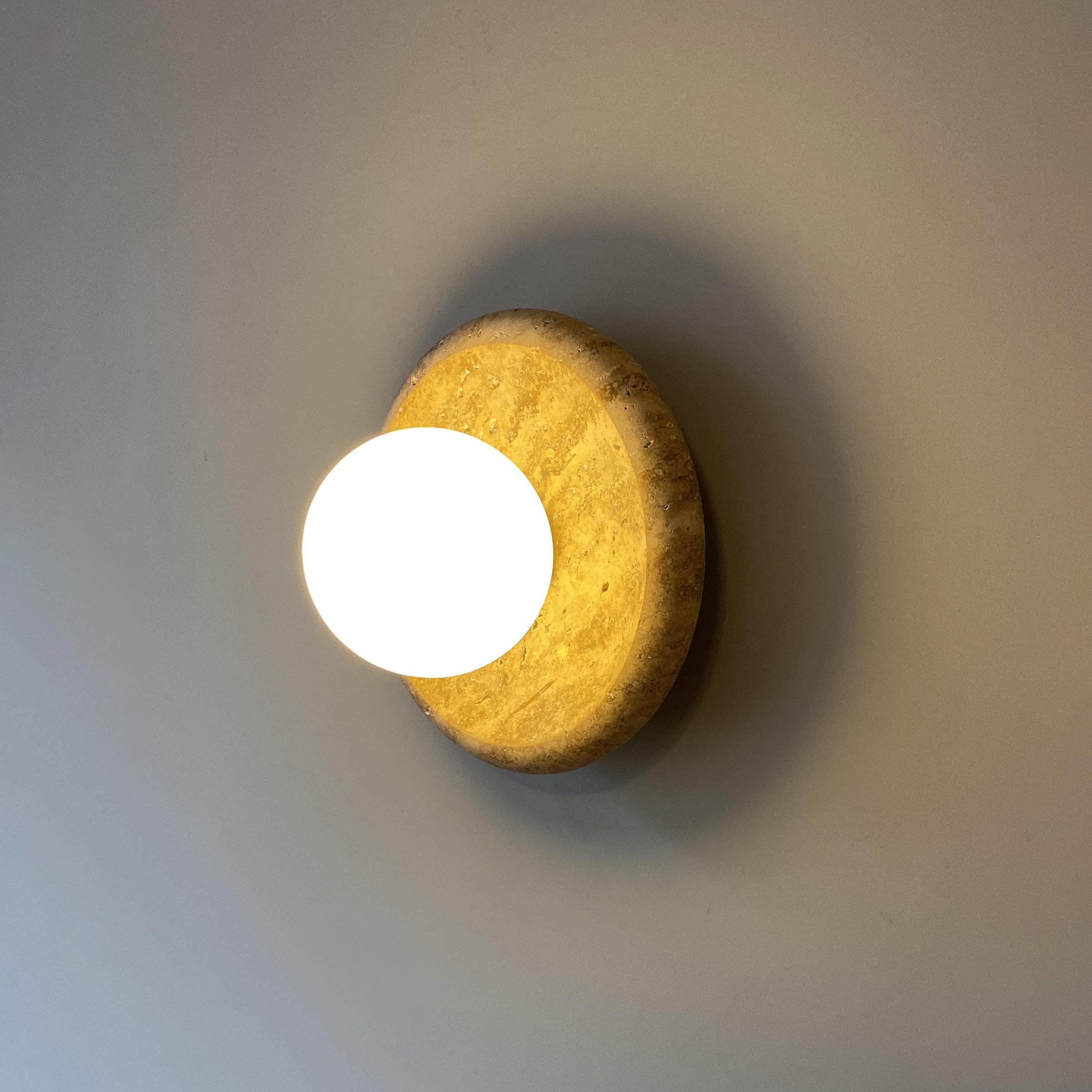 Close-up view of the natural texture of the travertine stone on the wall lamp.
