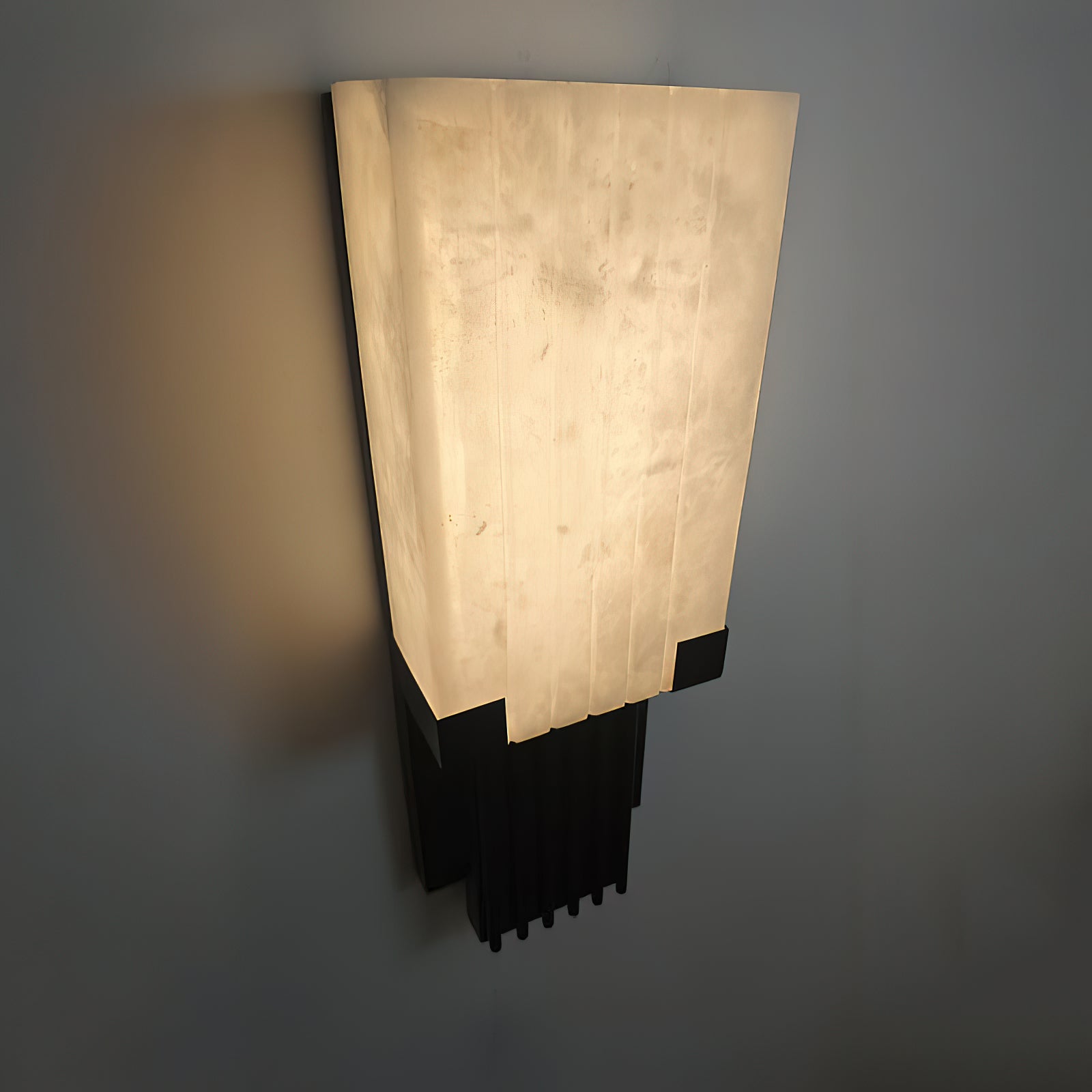 The Ariel Alabaster Wall Lamp shown against a textured wall.
