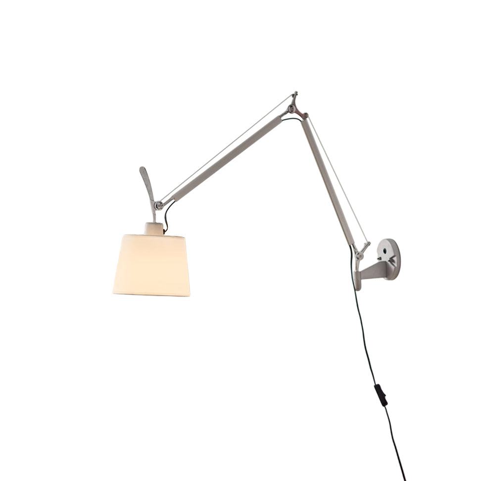 Costanza plug-in swing-arm wall lamp in silver, extended over a modern sofa.
