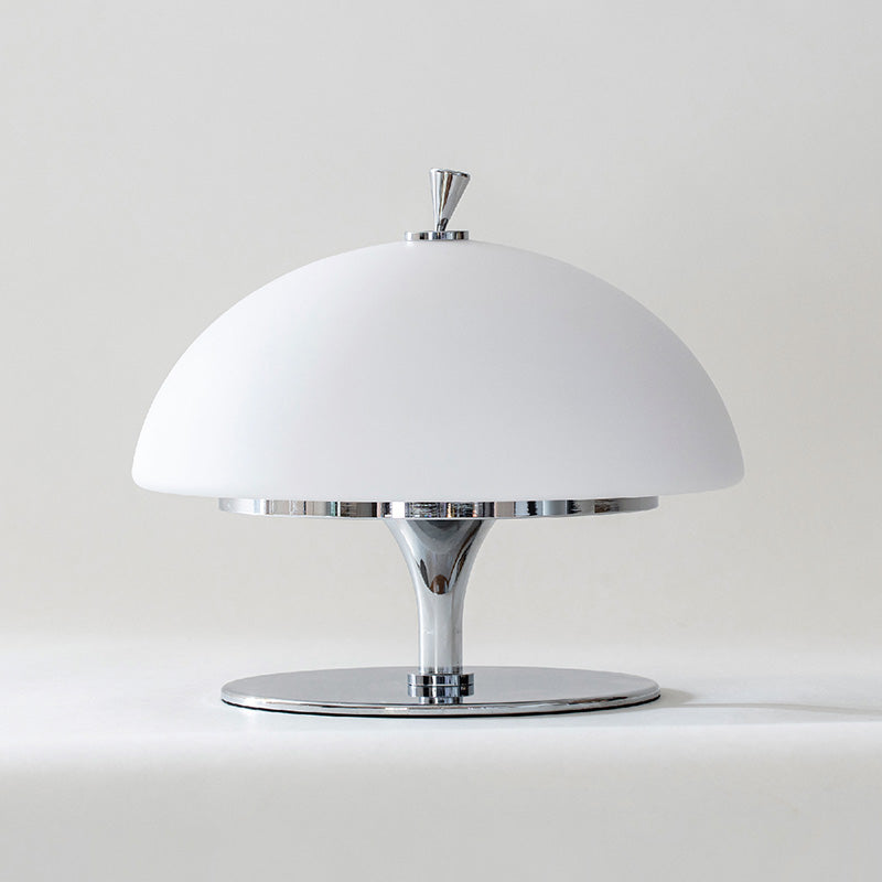 Lifestyle image featuring the Beret Table Lamp on a side table next to books.