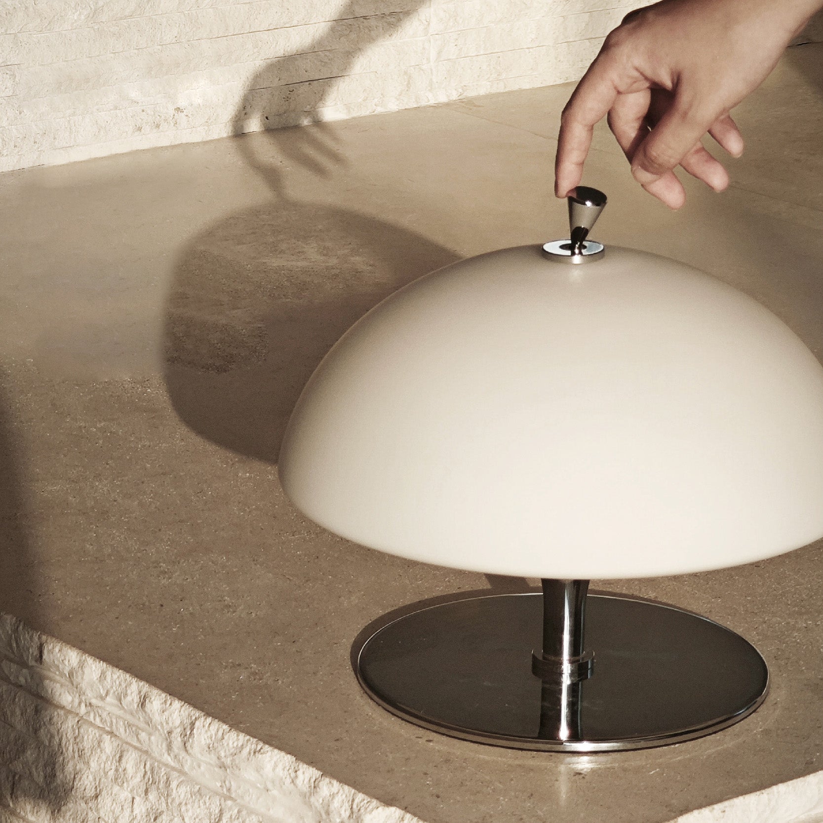 Close-up of the chrome touch control dial on top of the Beret Table Lamp.