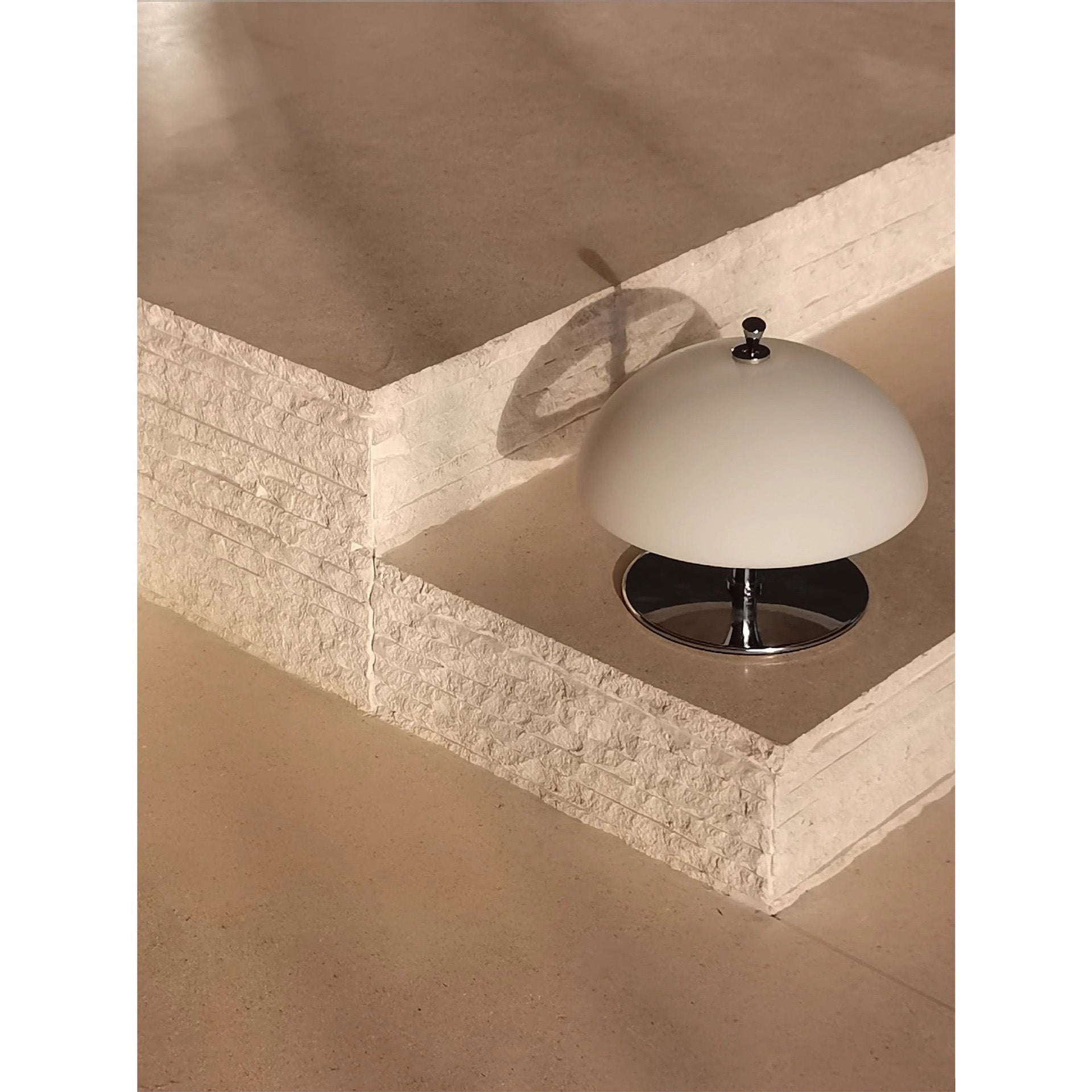 The Beret Table Lamp turned on, casting a warm and inviting glow.