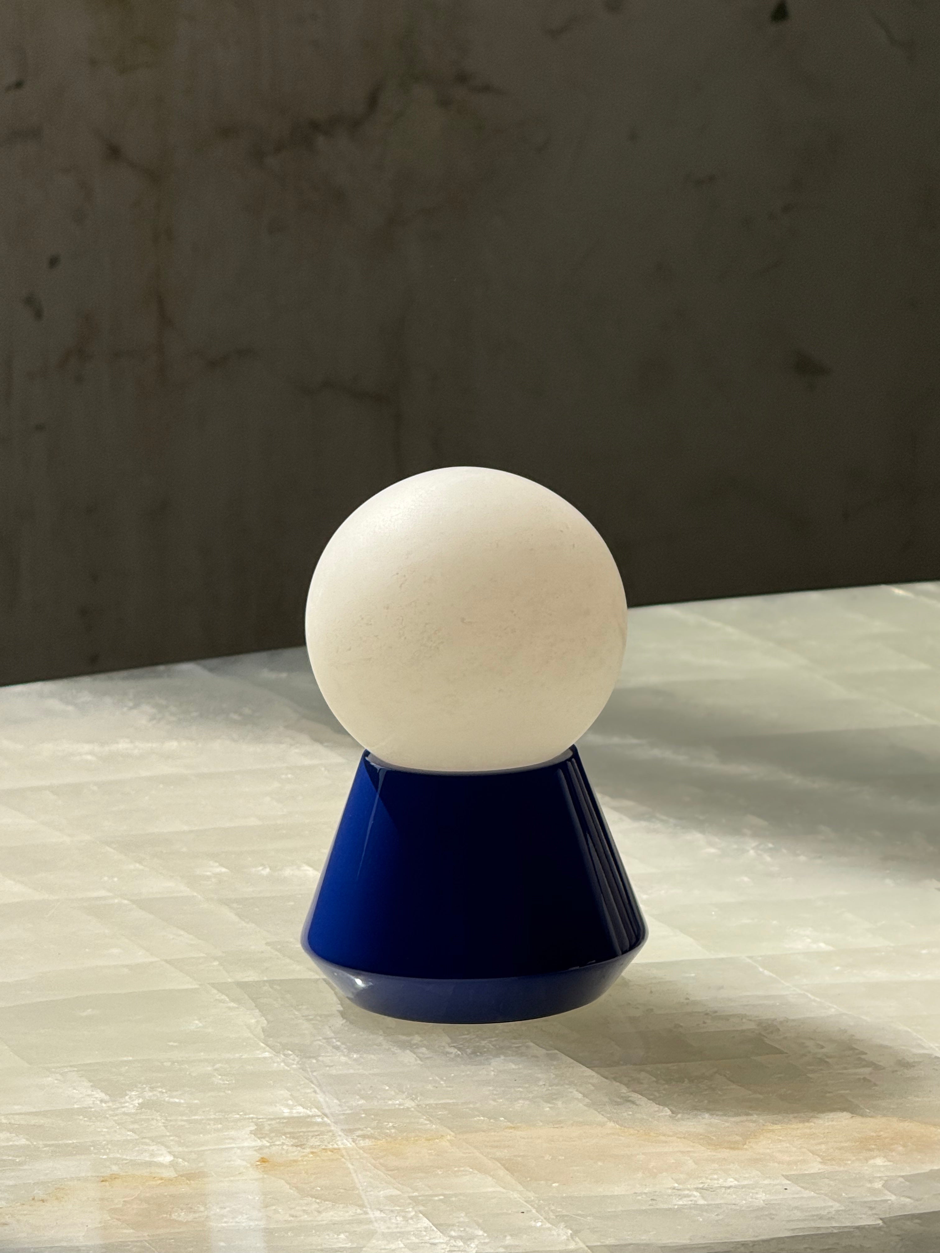 The portable Bilia Mini Table Lamp held in hand to show its compact size.