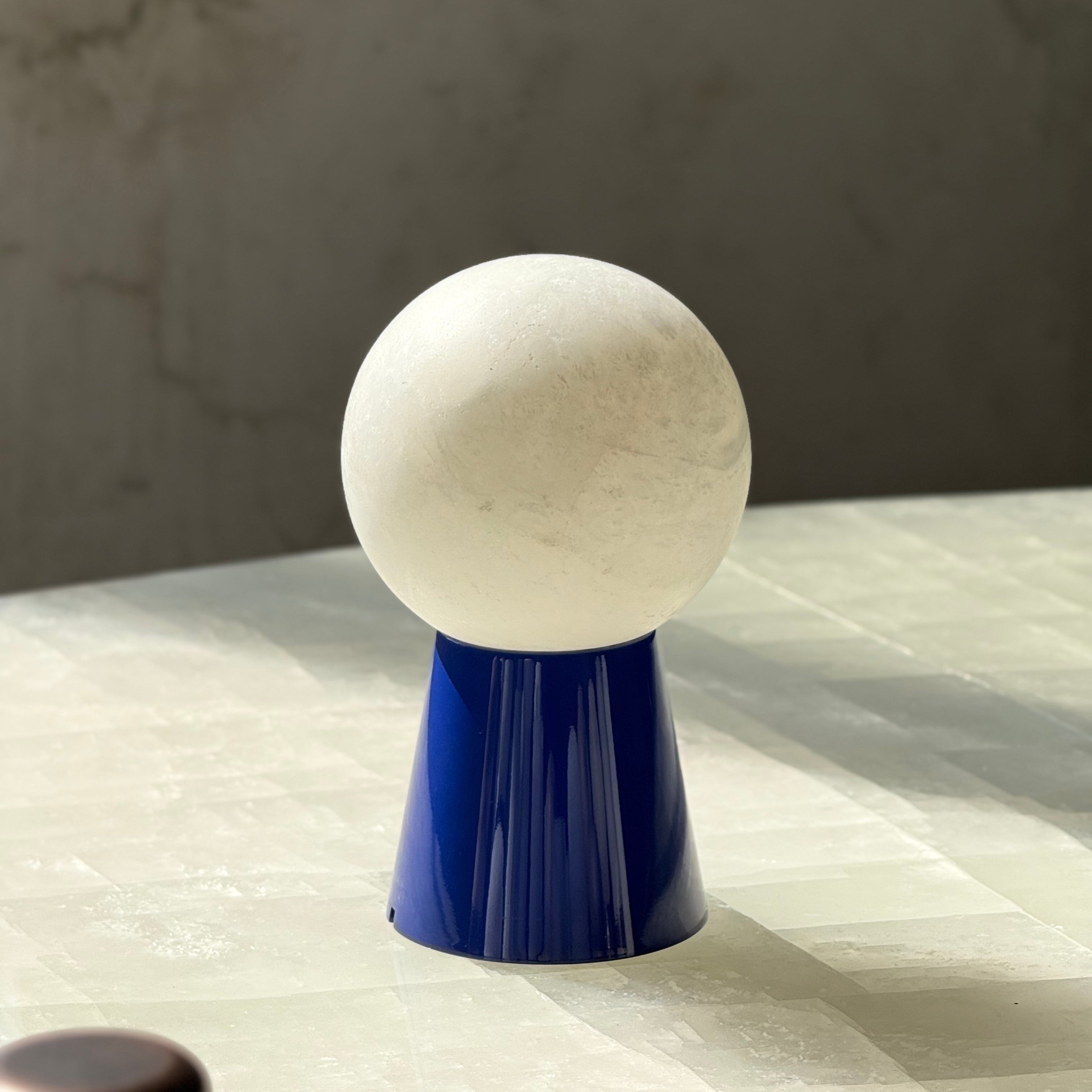 Detailed shot of the sleek metal base of the white table lamp.