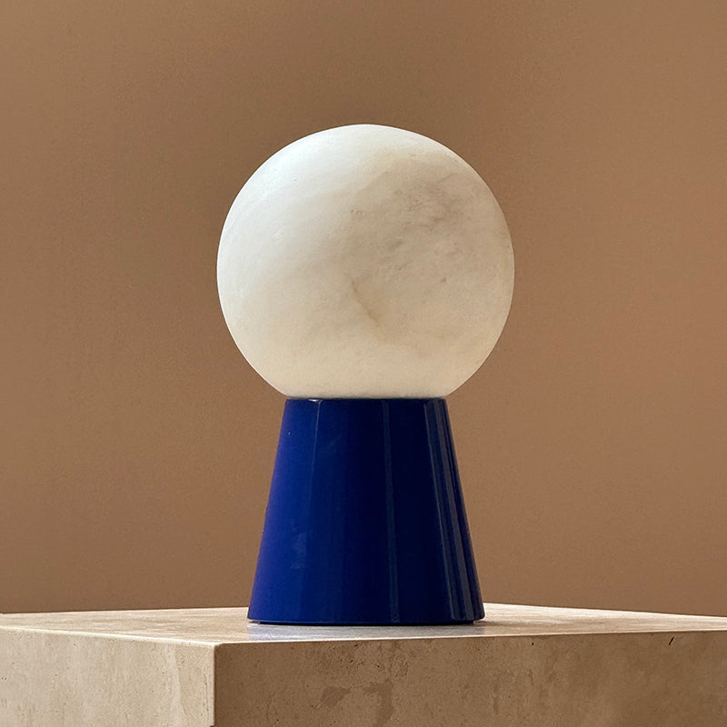 The blue Bilia Mini Table Lamp against a dark, moody background.