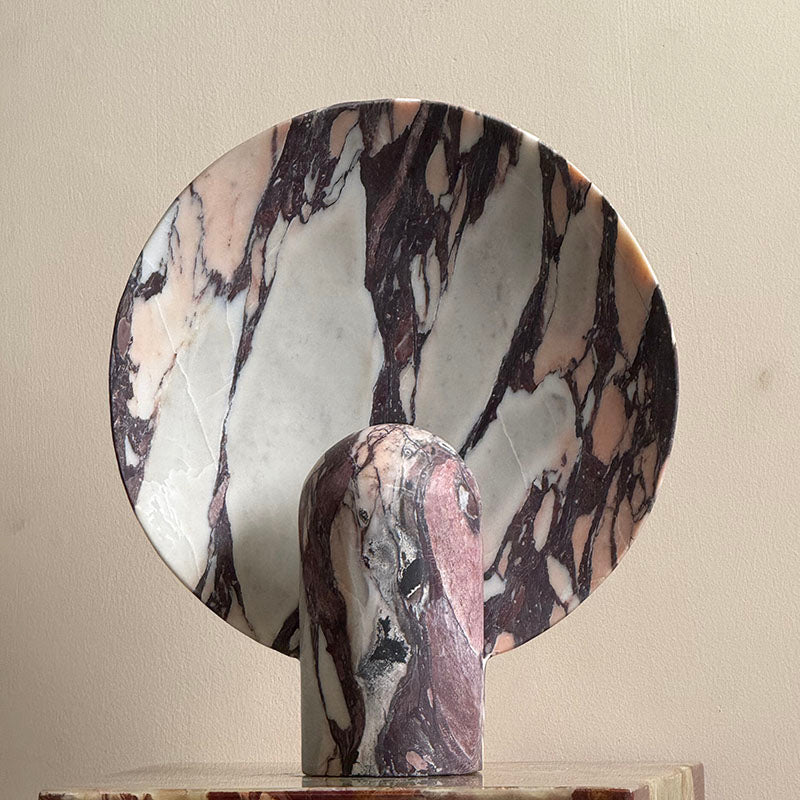 Beige travertine Fan Table Lamp with its warm light on.