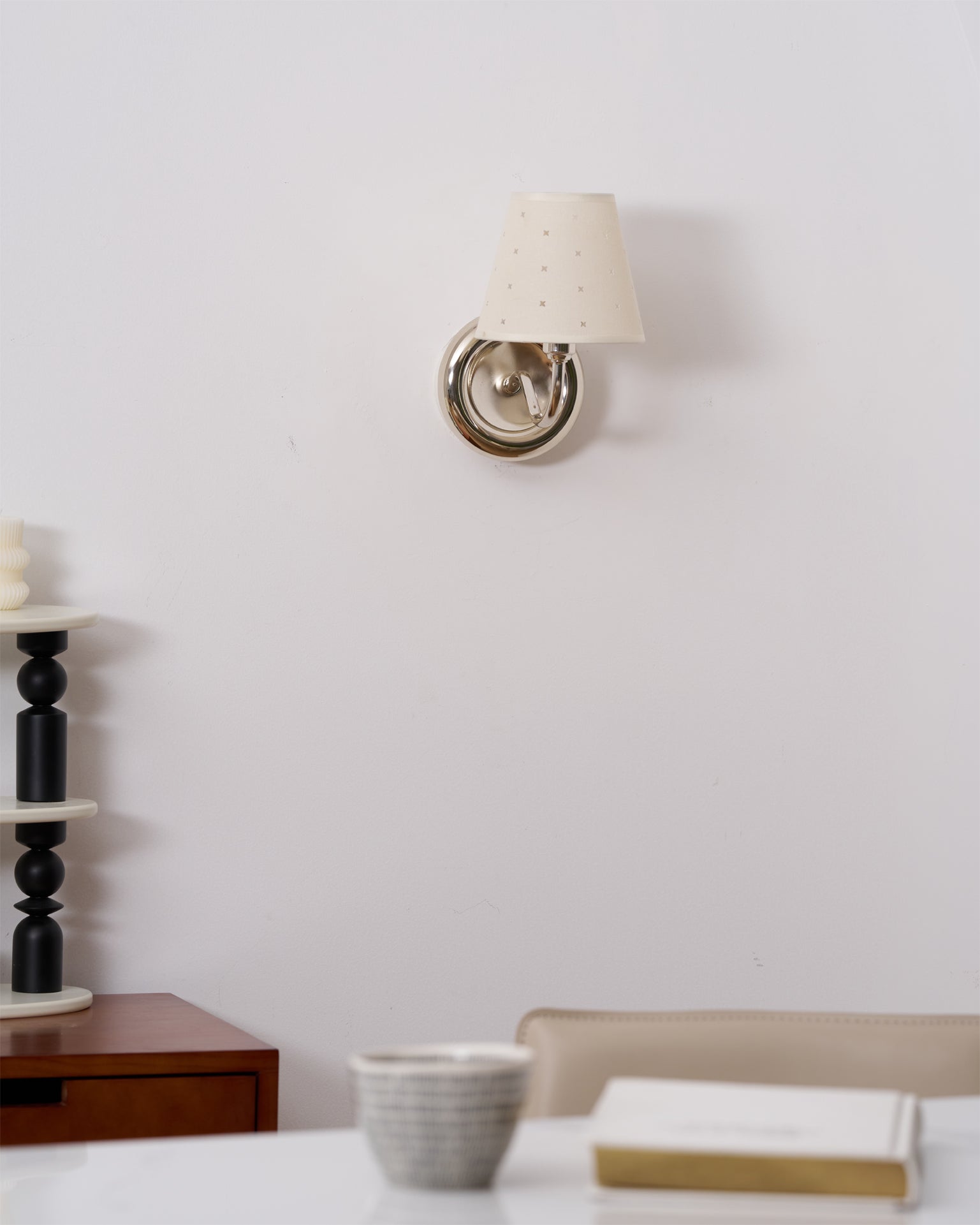 A pair of gold Caleb sconces creating a symmetrical look beside a bed.