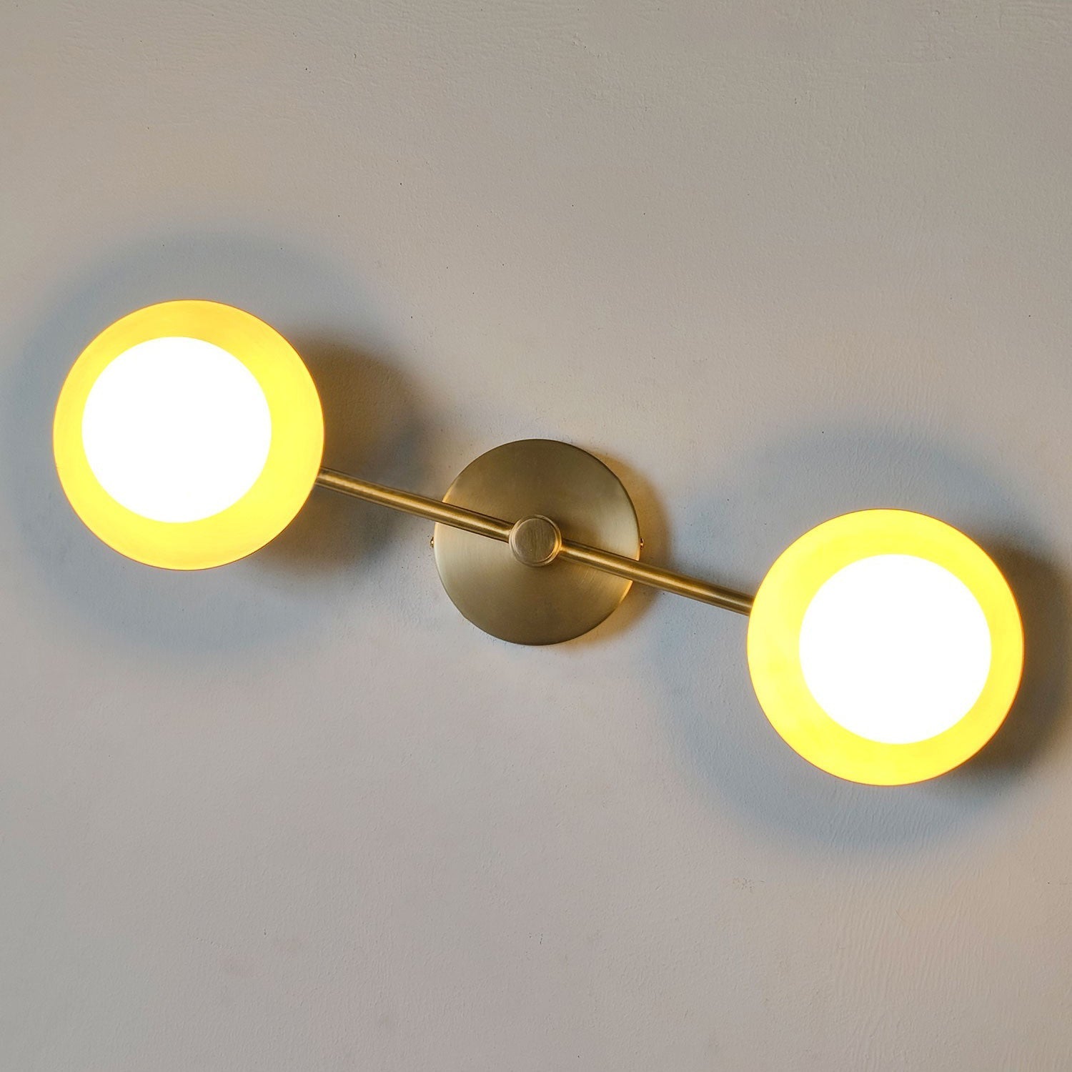 Lifestyle image of the Cara Alabaster Wall Lamp installed in a chic hallway.