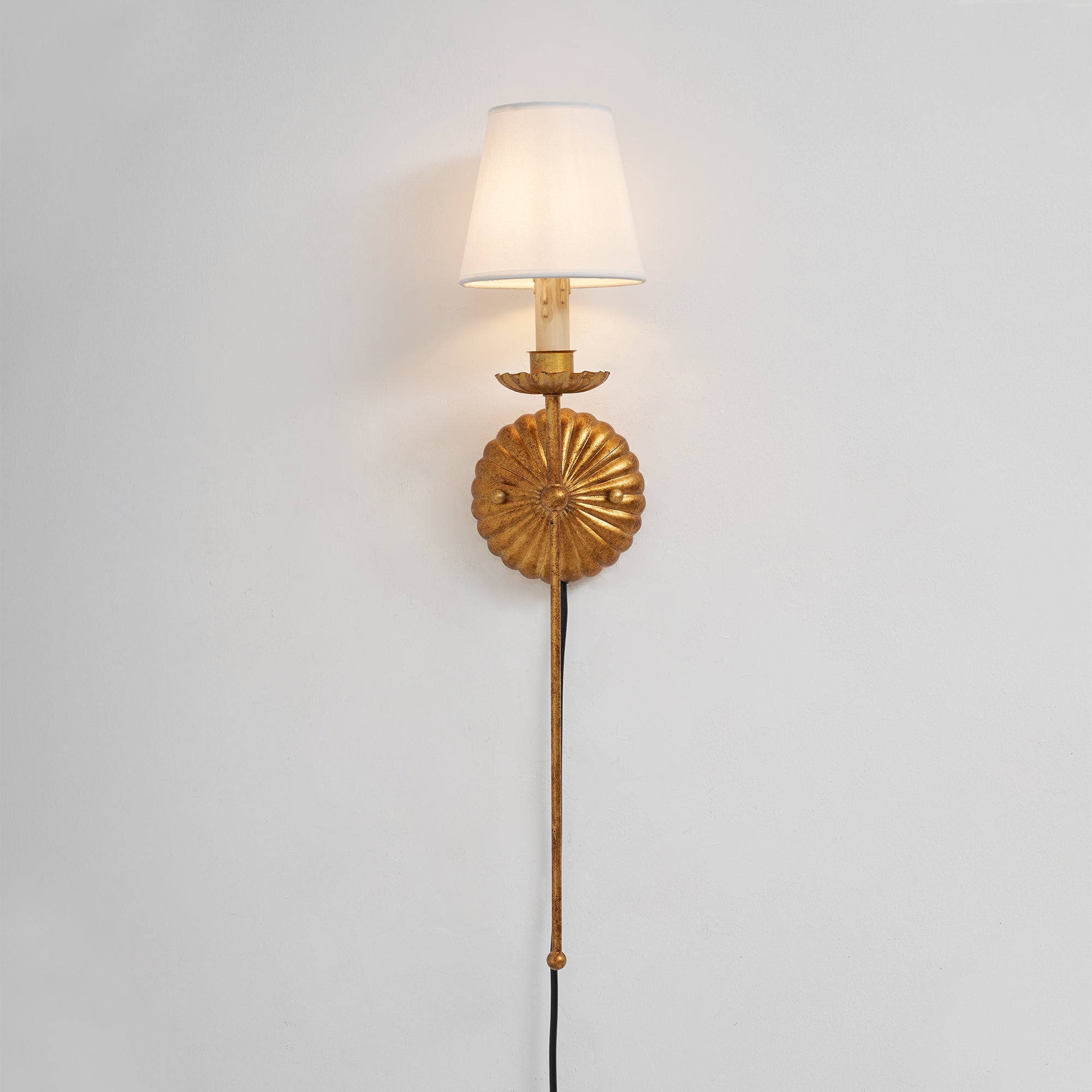 The wall sconce shown lit, casting a warm and inviting glow.