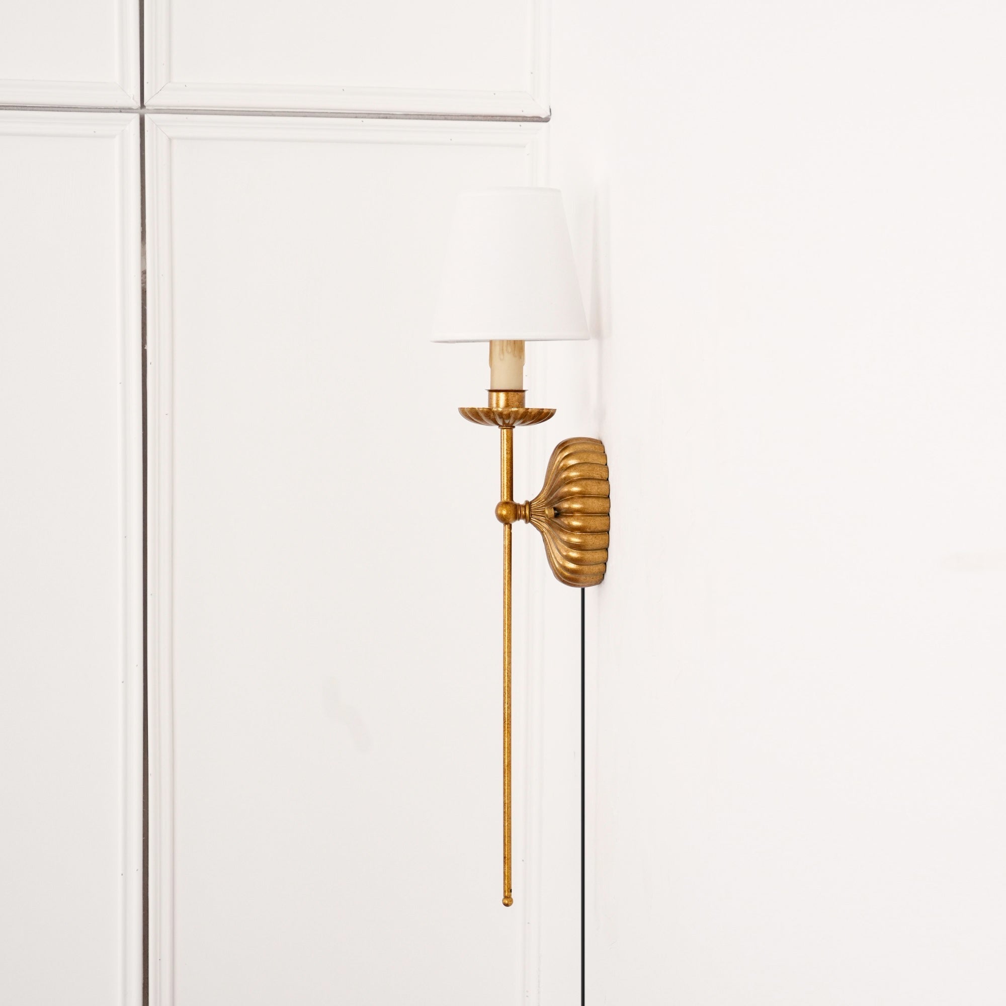Lifestyle image of the single-arm sconce used as a bedside reading light.