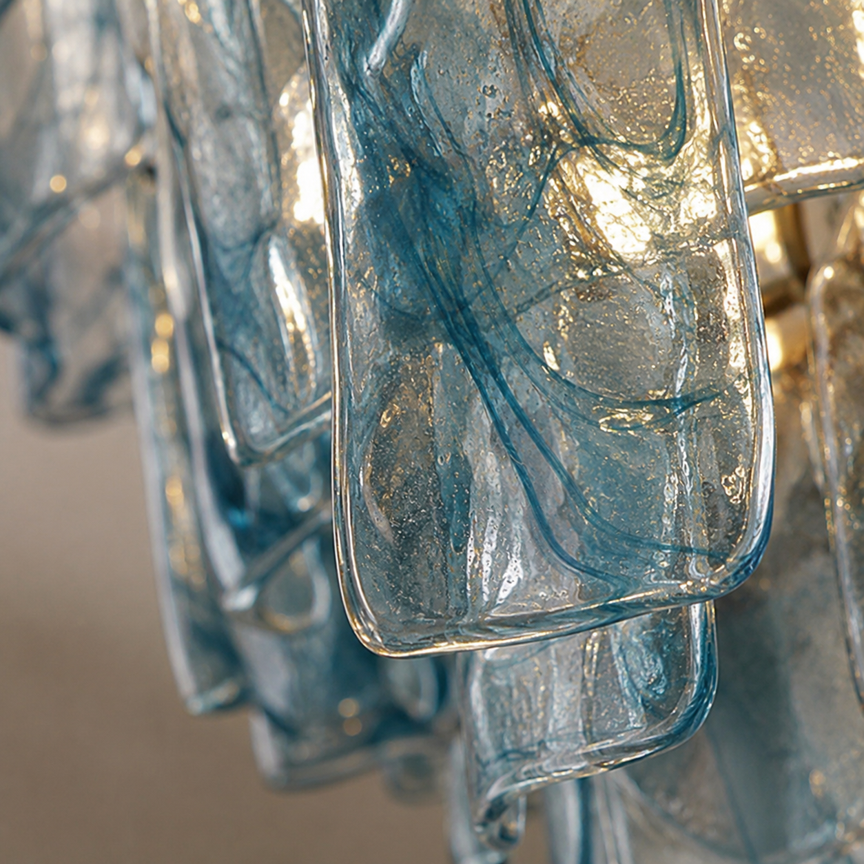 Detailed shot of the blue glass panels and the chandelier's metal frame.