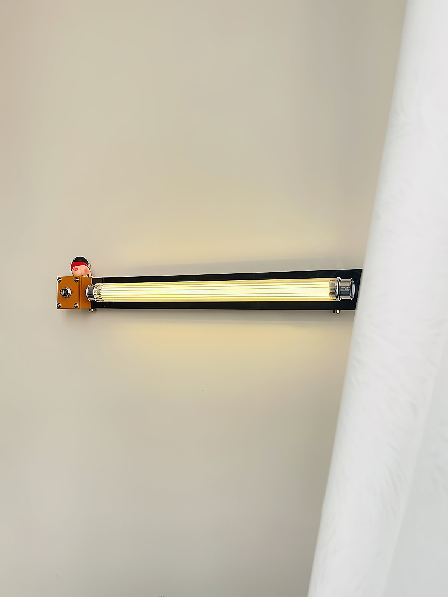 Cutshall Wall Lamp illuminated, casting a warm, ambient glow.