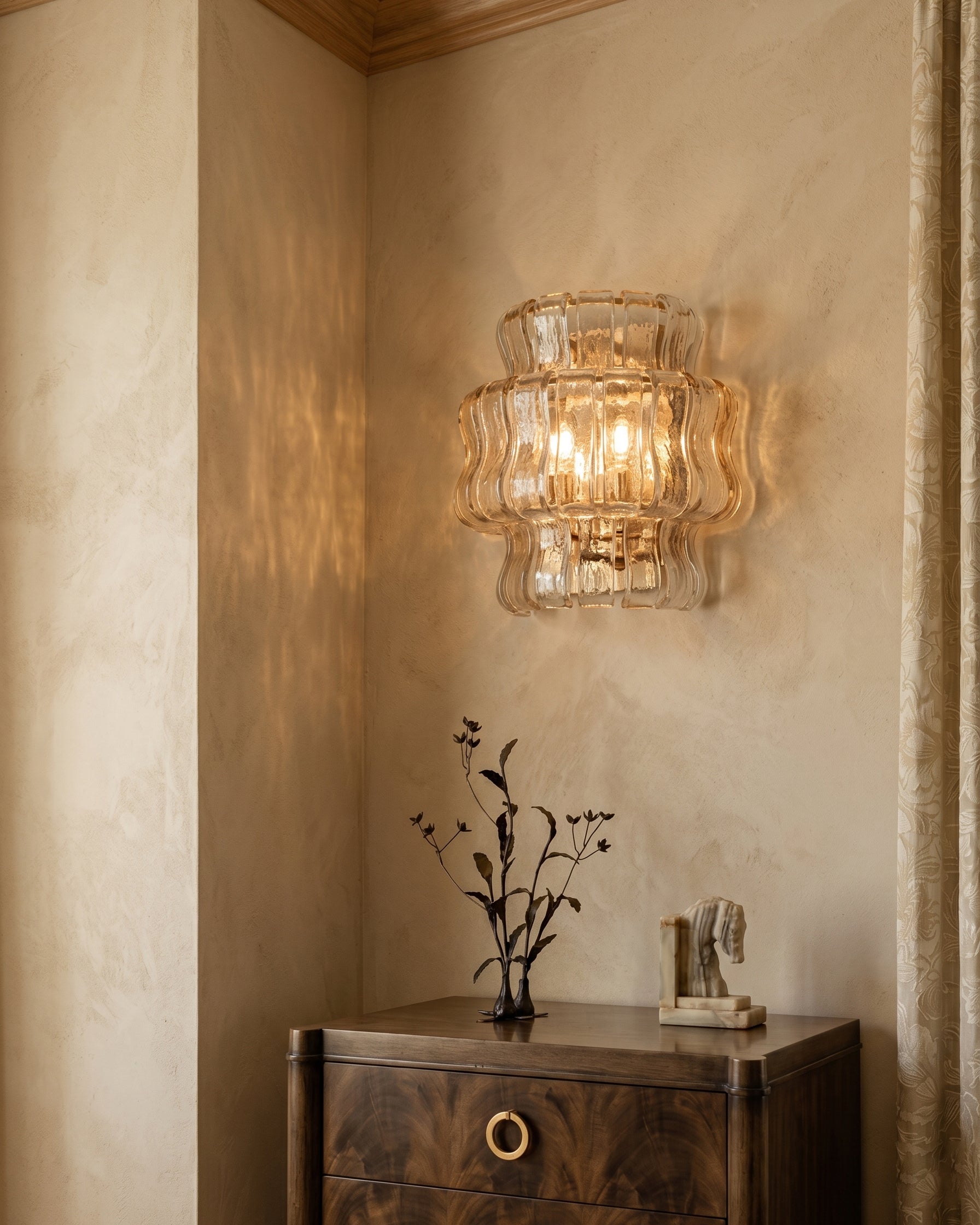 The Albano Wall Lamp in amber glass casting a warm glow.