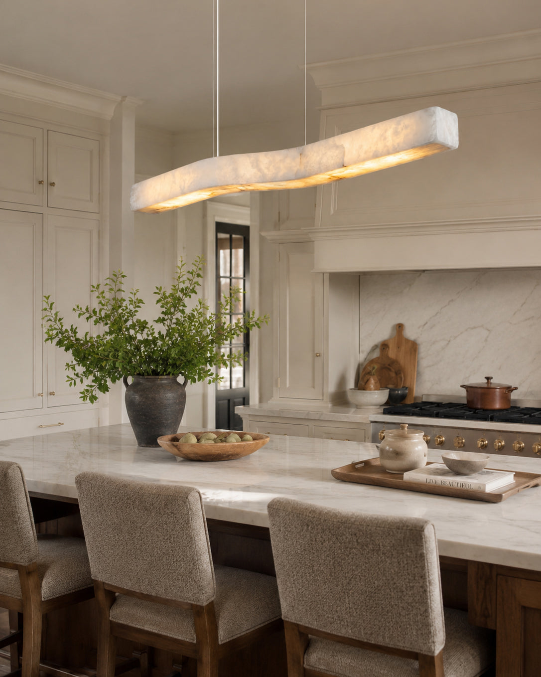 The Camur chandelier illuminated, casting a warm glow through the alabaster stone.