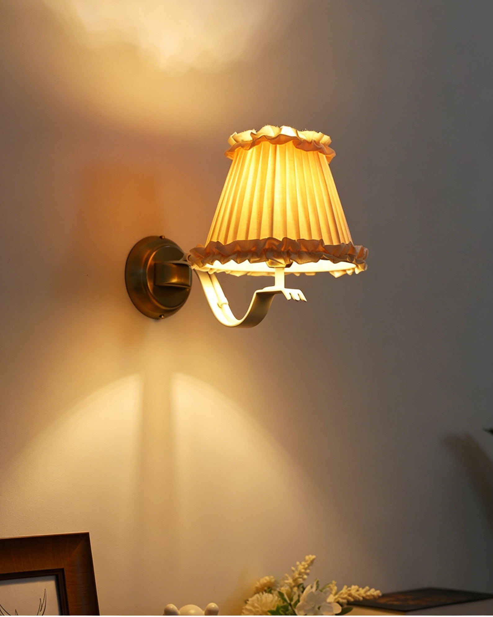 The wall sconce shown illuminated, casting a warm glow.