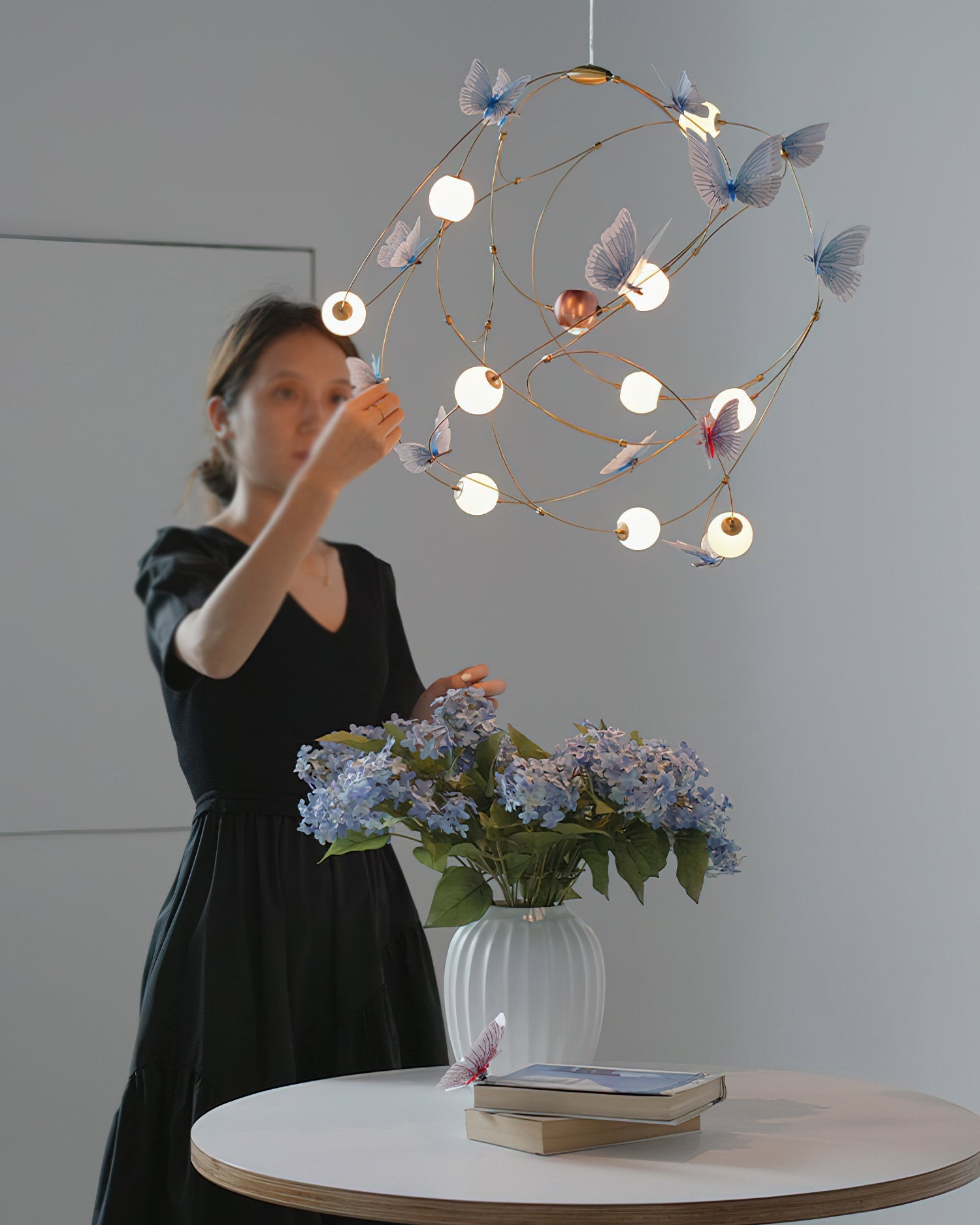 The Faye Orbit Butterfly Chandelier illuminated at night, casting a starry glow.