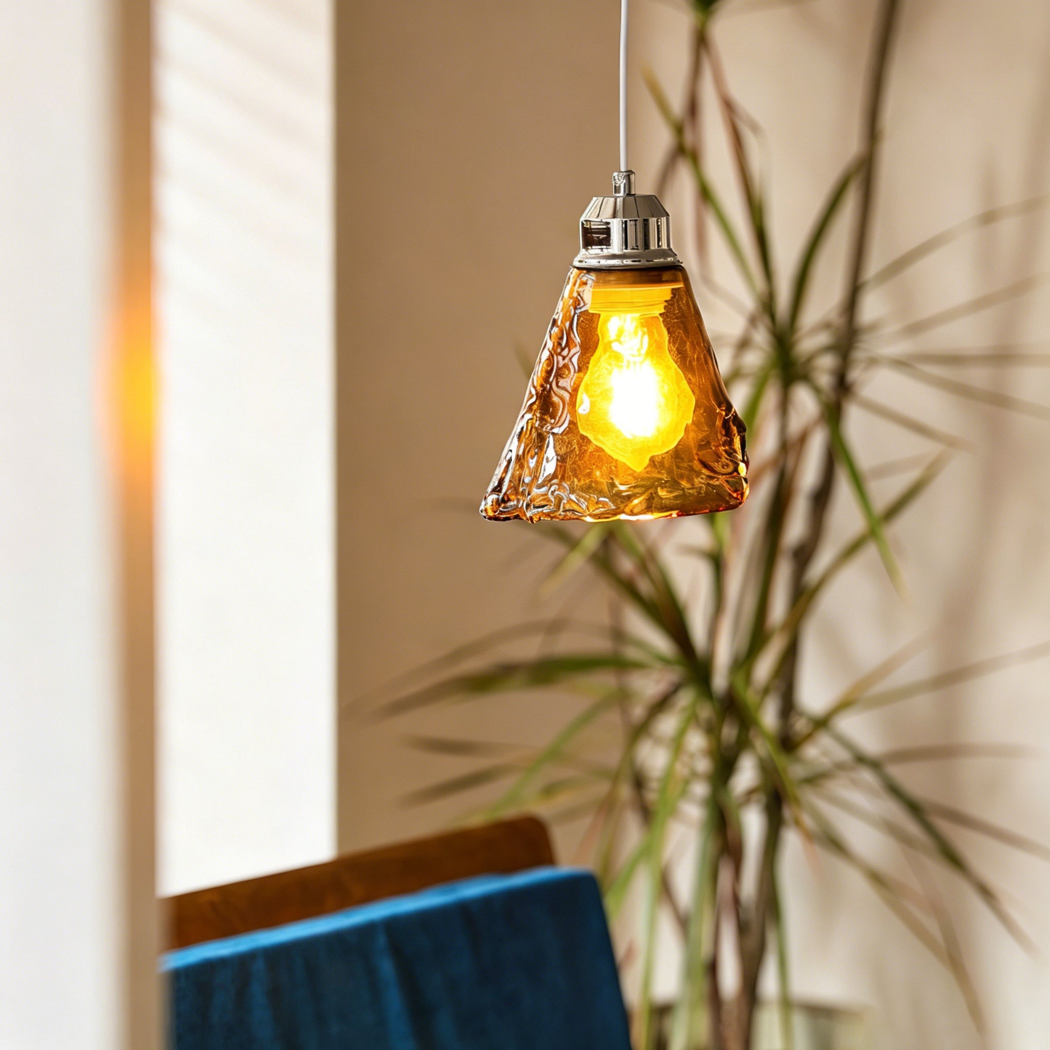 Close-up view of the hand-blown amber glass shade of the Tiro Pendant Light, showing its unique texture.