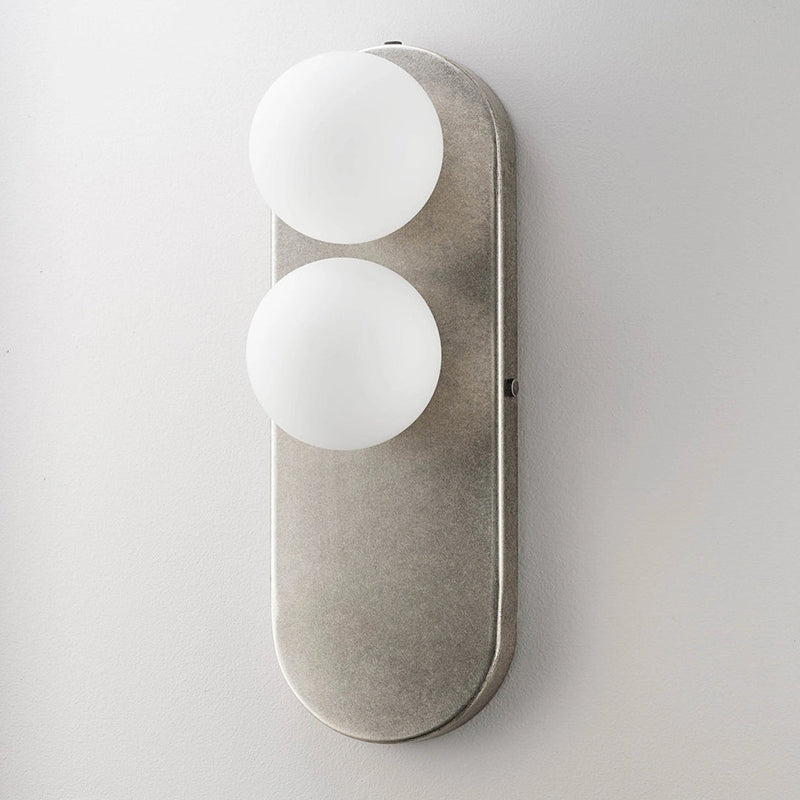 Close-up of the Eccolo Wall Lamp's rounded glass lampshade and iron fixture.