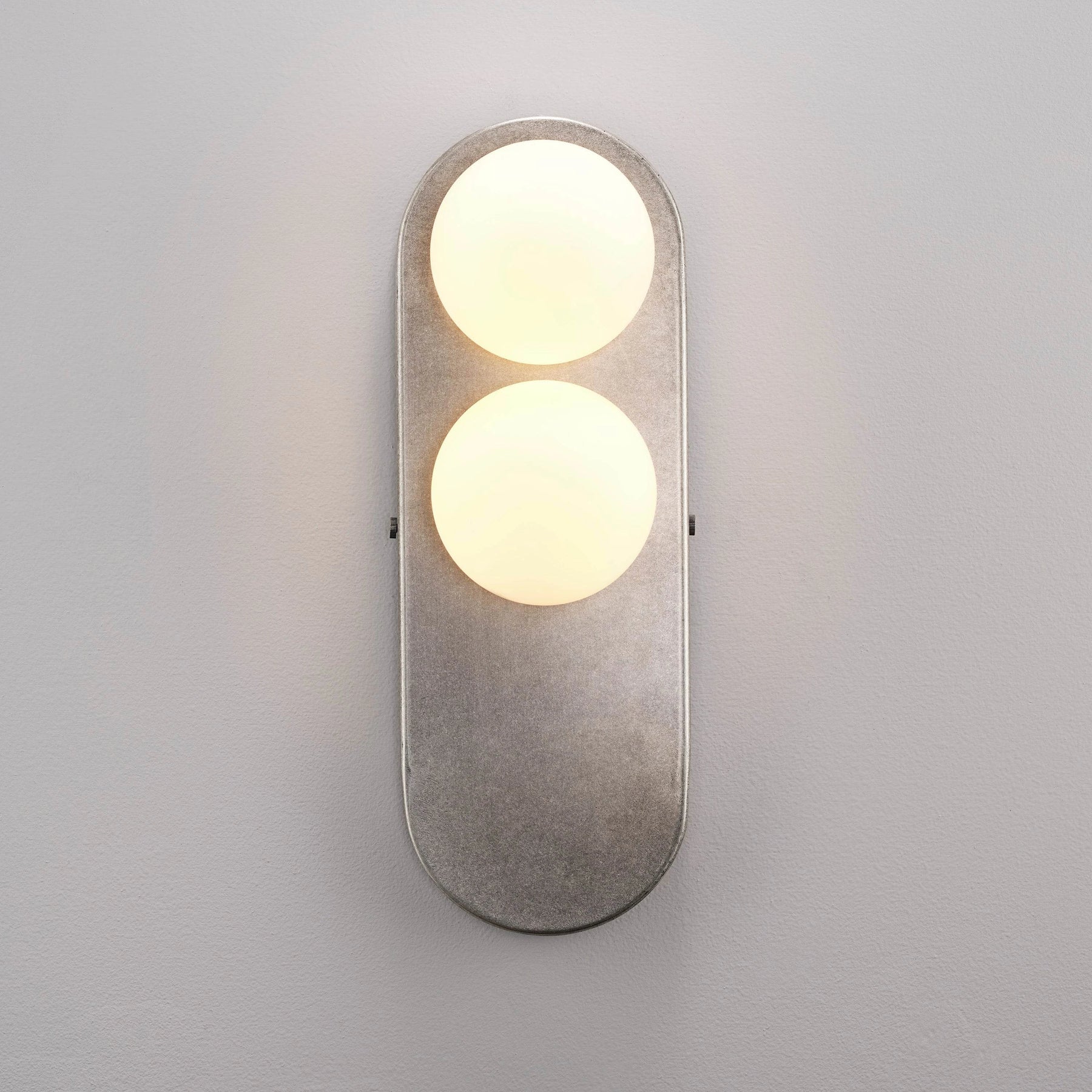 Eccolo Wall Lamp illuminated in a dark room, casting a warm glow.