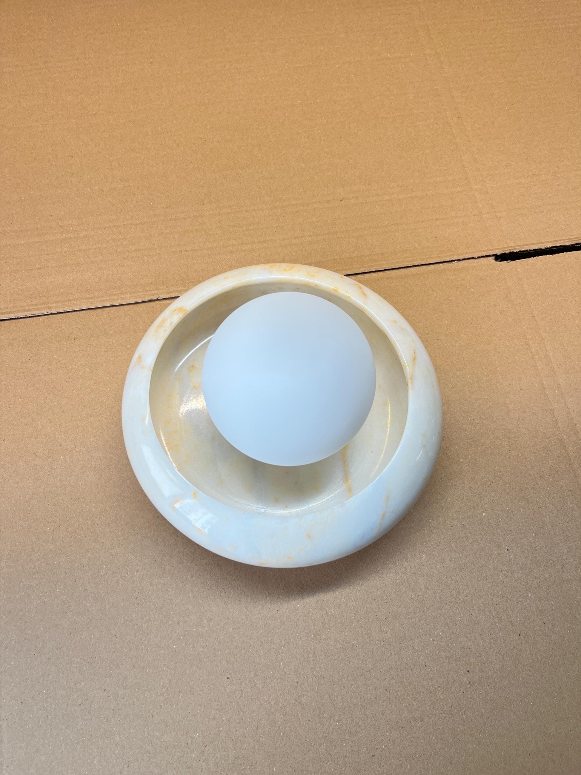 The Eclipse Marble Wall Sconce shown against a dark background to emphasize its shape.