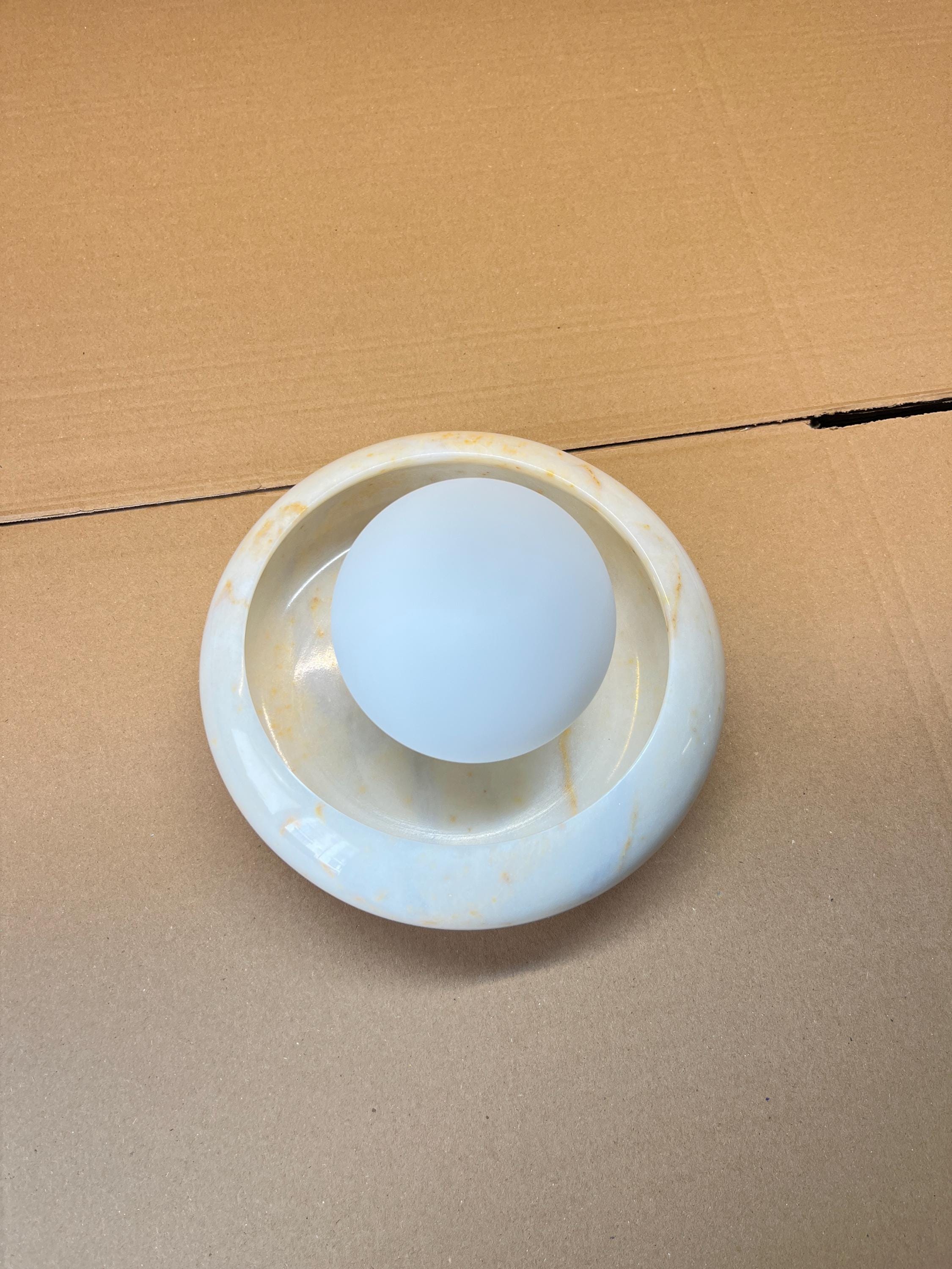 The Eclipse Marble Wall Sconce shown against a dark background to emphasize its shape.