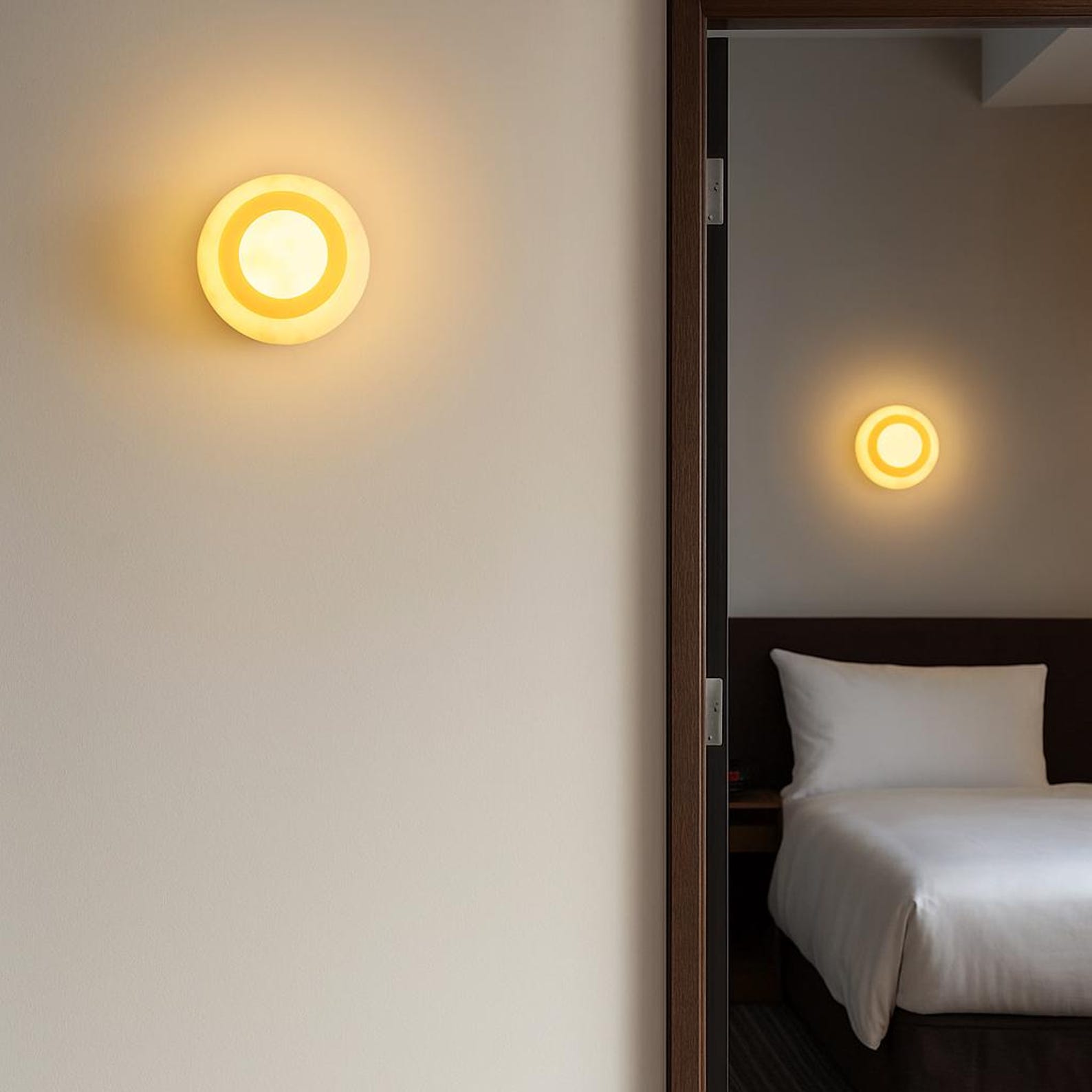 The Eclipse Marble Wall Sconce installed in a modern hallway, casting a warm glow.