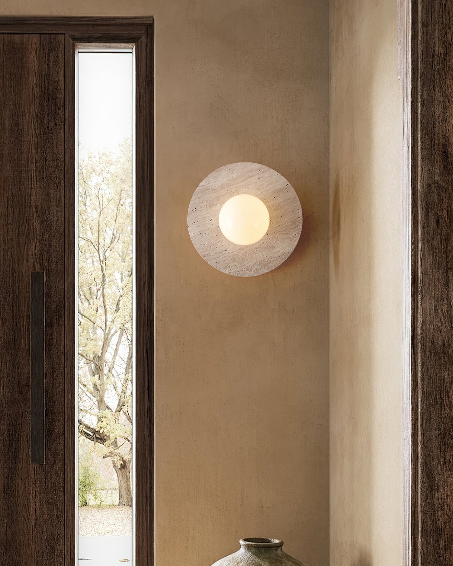 Elira Travertine Wall Lamp illuminating a modern living room.