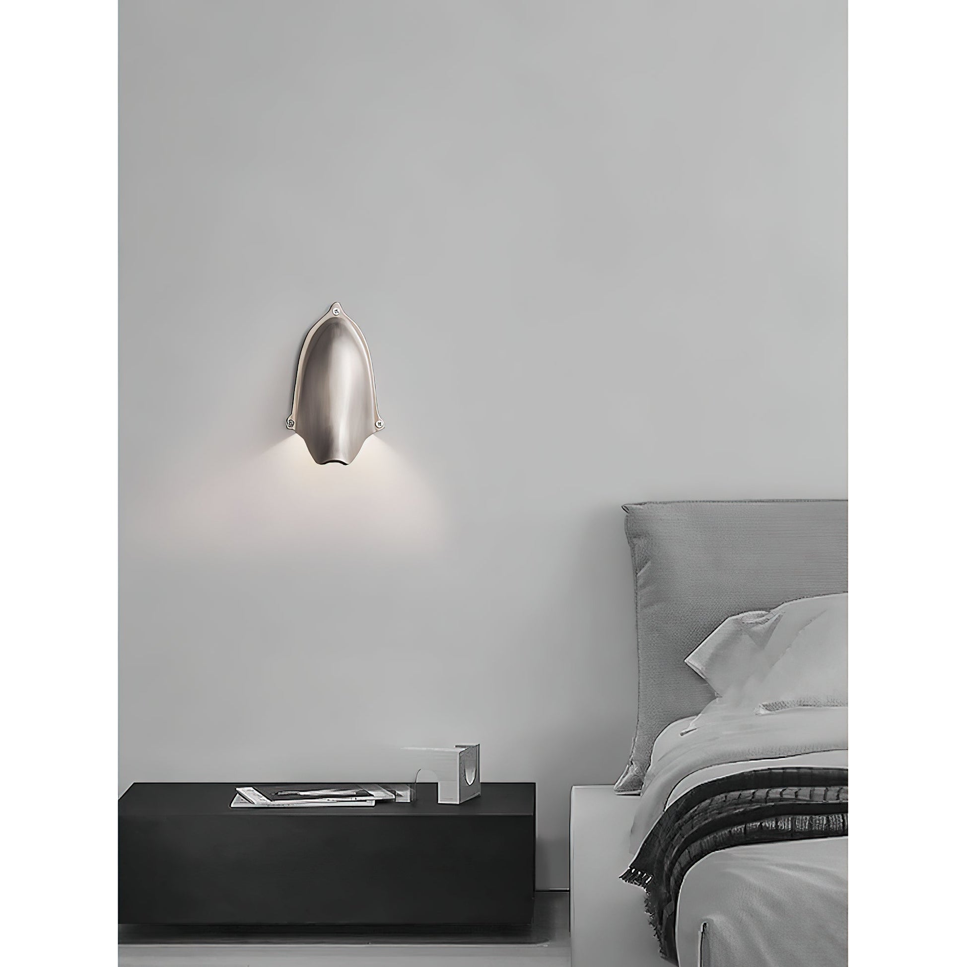 Enoki Wall Lamp in Antique Brass, casting a warm glow.