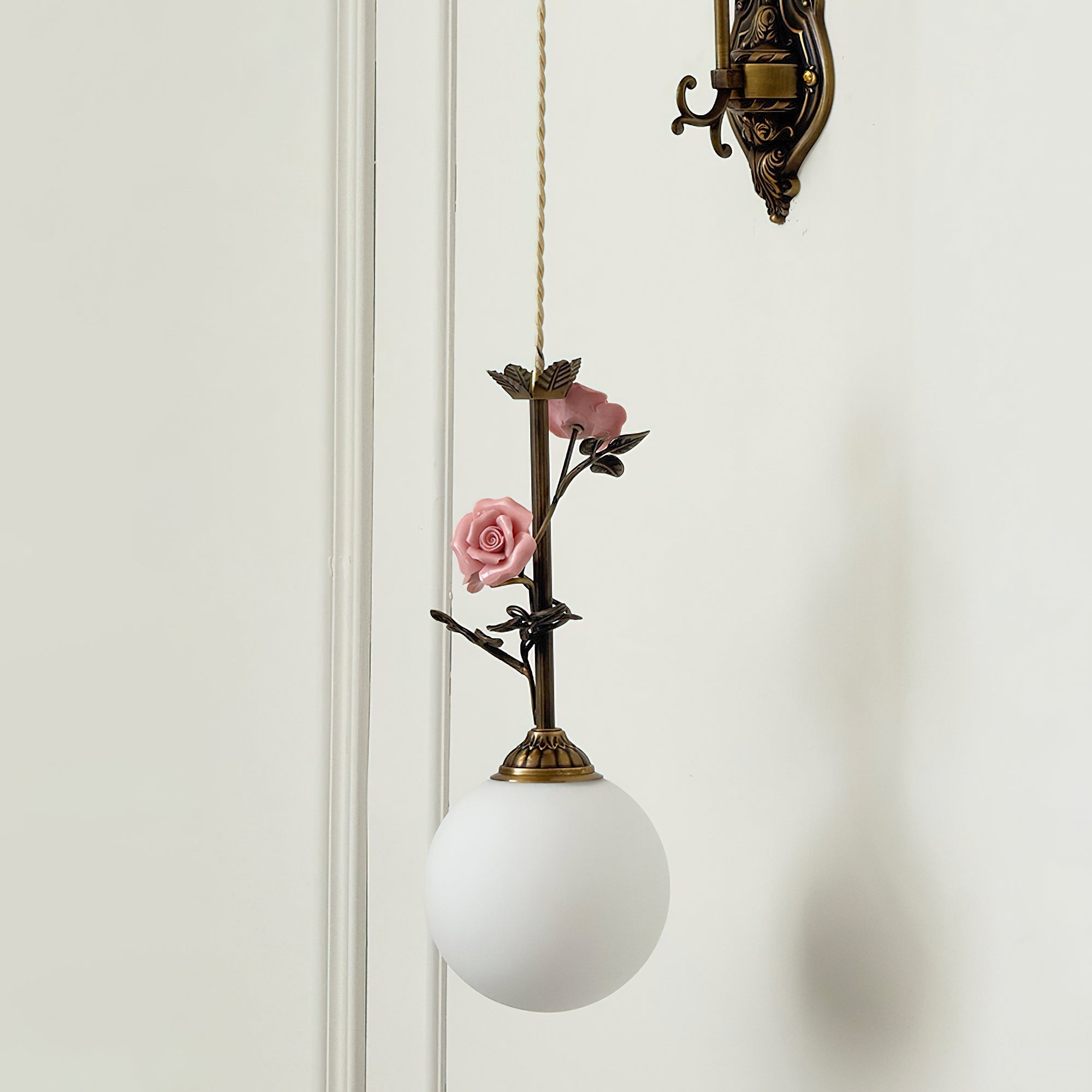 The blue glass rose sconce, unlit, against a light wall.