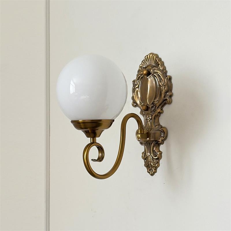 Lit Evelyn Wall Lamp in clear finish on a dark background.