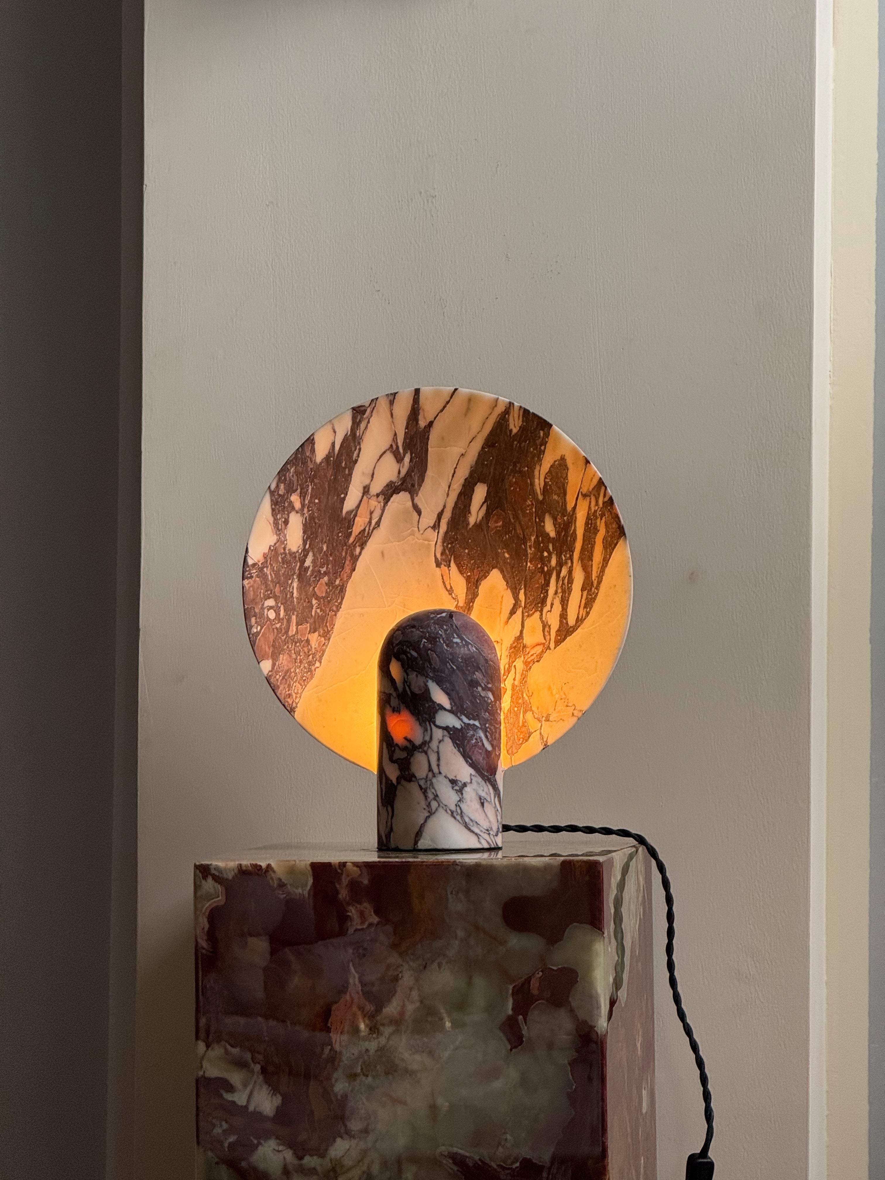 The beige travertine Fan Table Lamp on a wooden console.