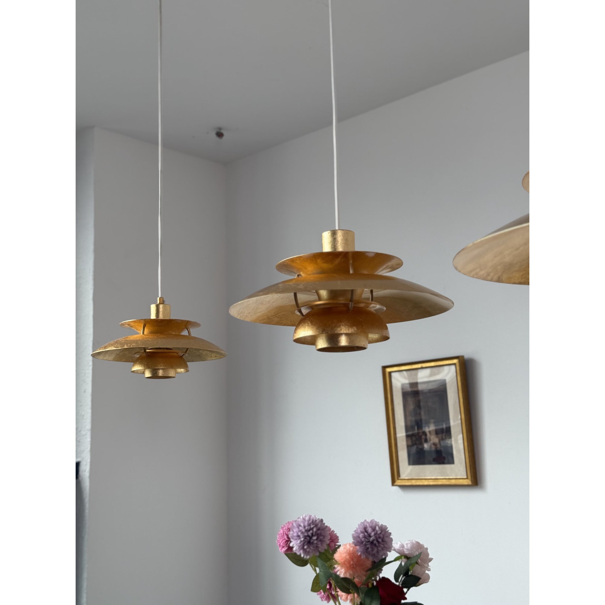A pair of gold foil lamps hanging together.