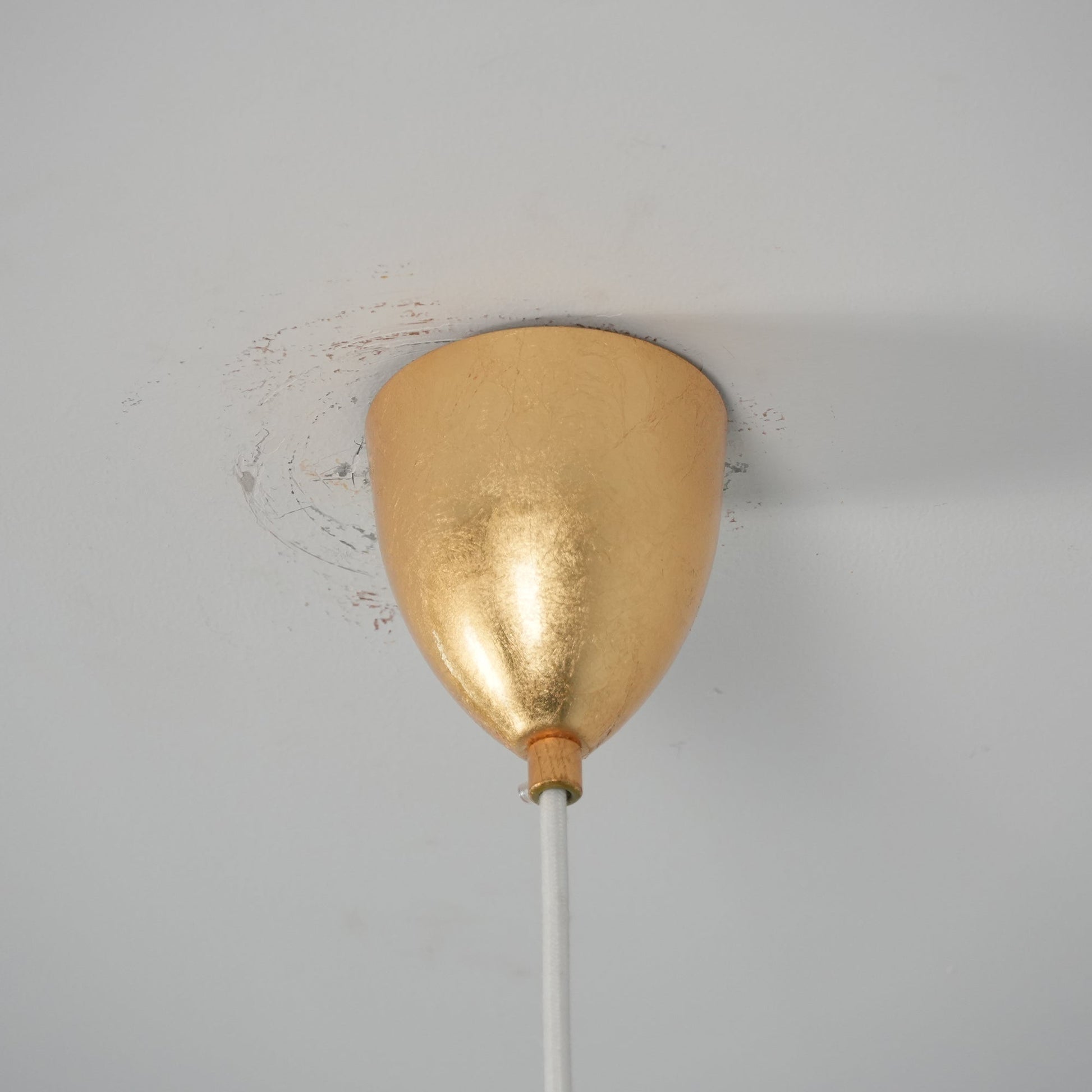 The three-head gold foil lamp illuminating a long wooden table.