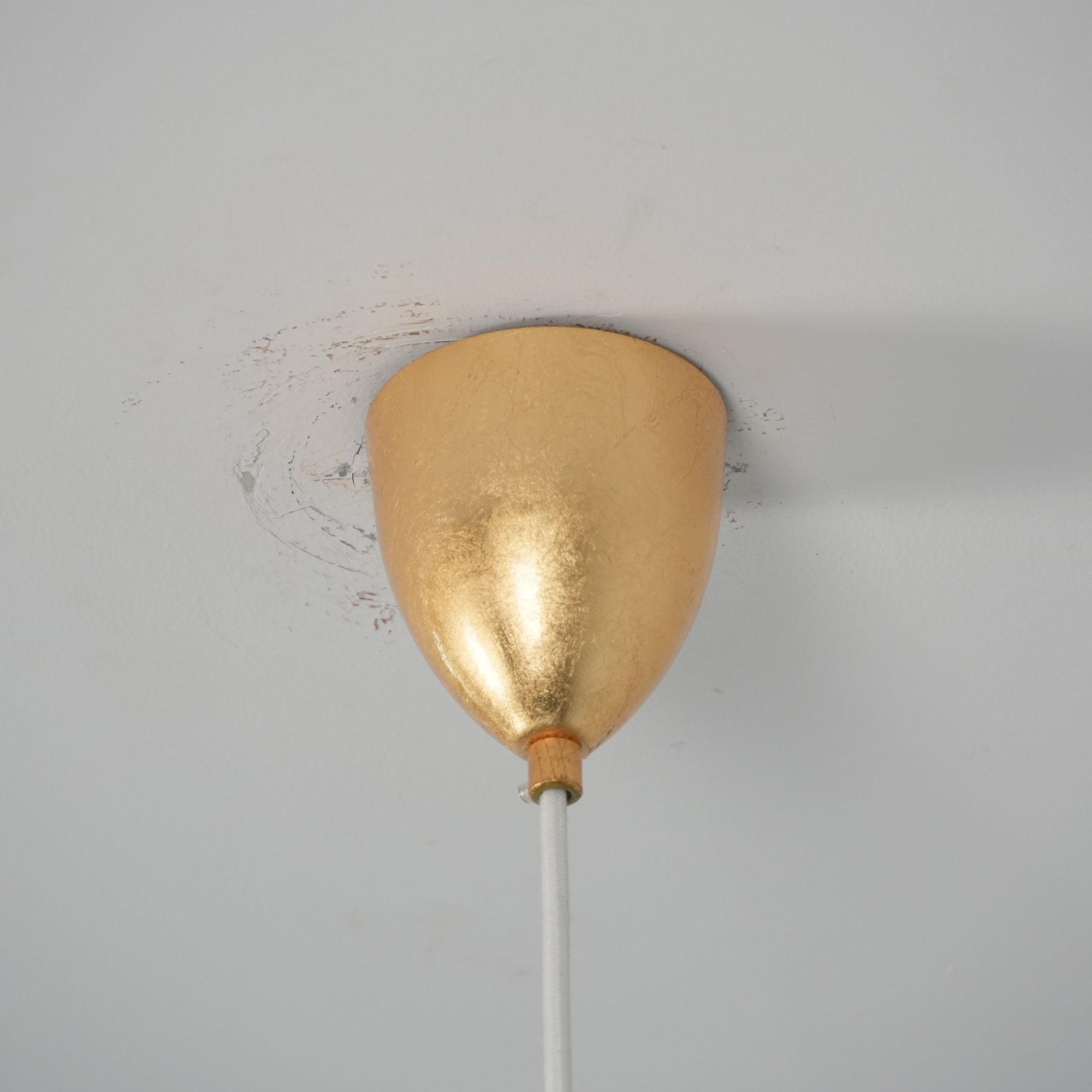 The three-head gold foil lamp illuminating a long wooden table.