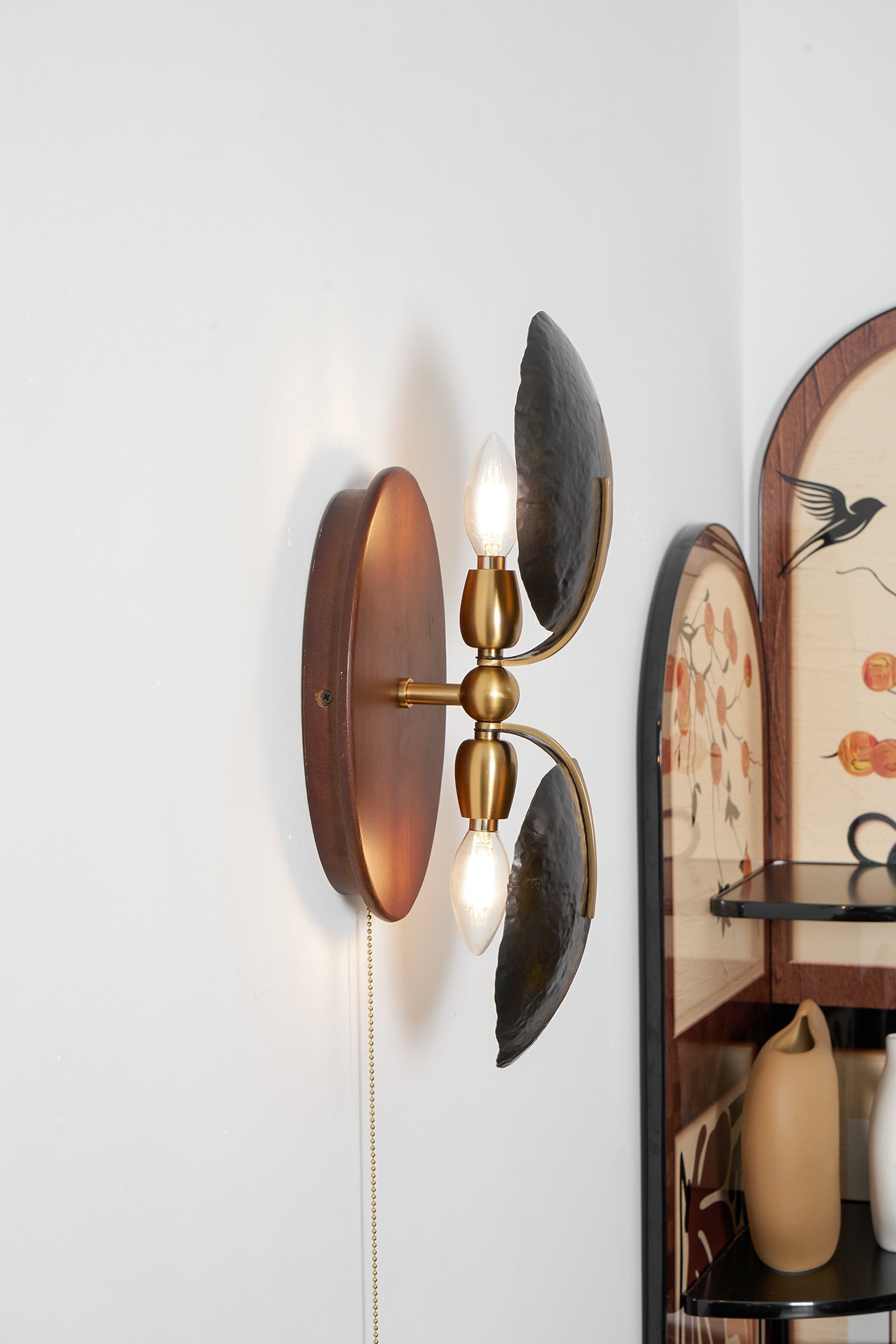 Greta Wall Lamp in black, mounted on a hallway wall.