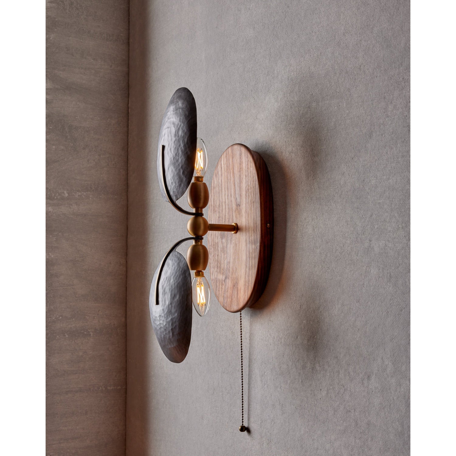 The Greta Wall Lamp providing ambient light in a cozy bedroom.