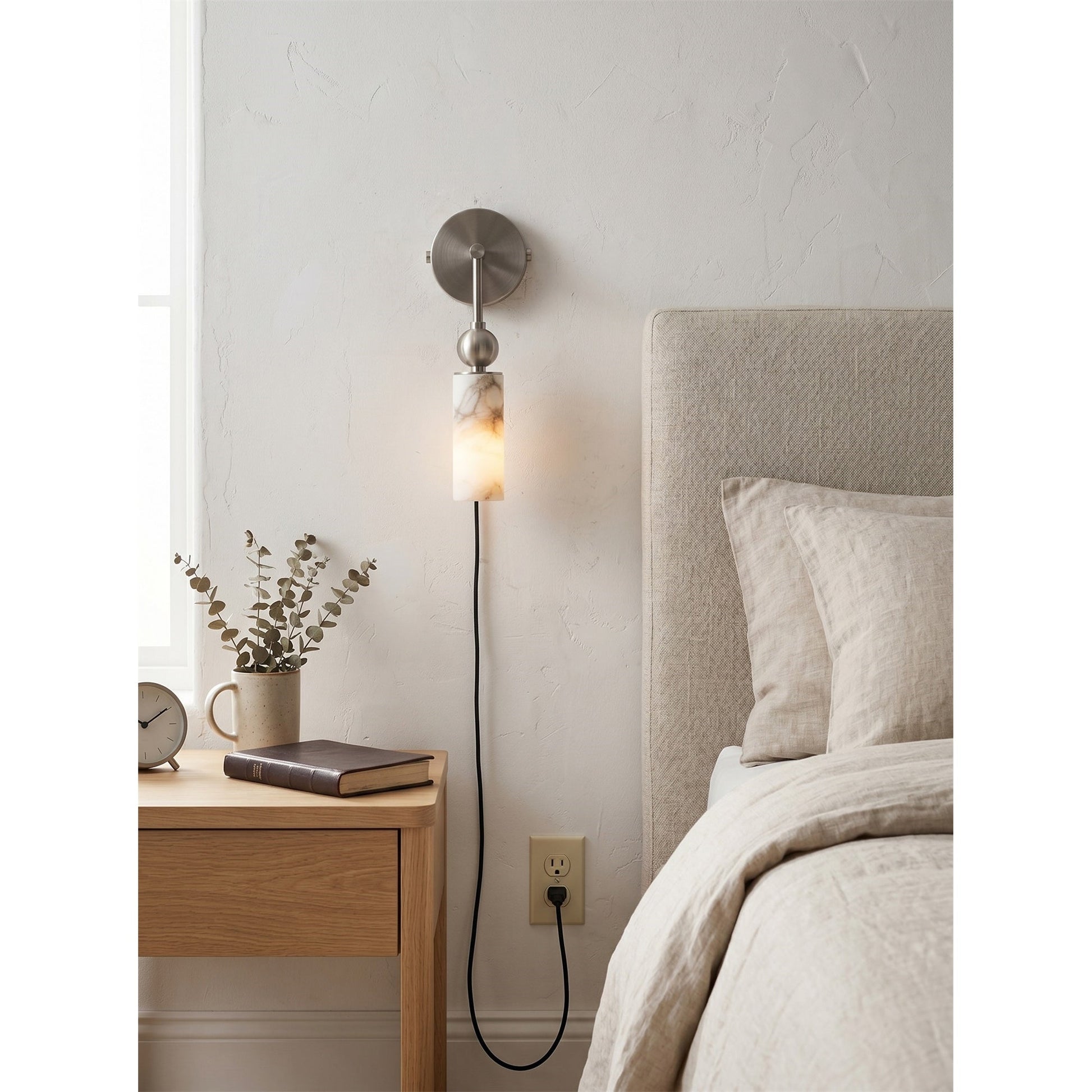 The alabaster sconce illuminated, casting a warm and inviting glow.