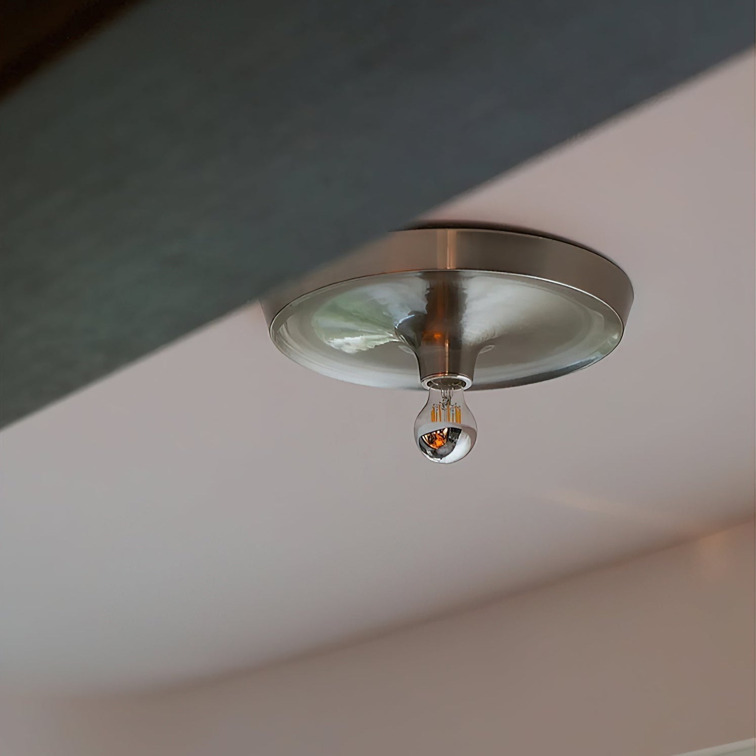 The minimalist aluminum wall lamp shown in a modern living room.