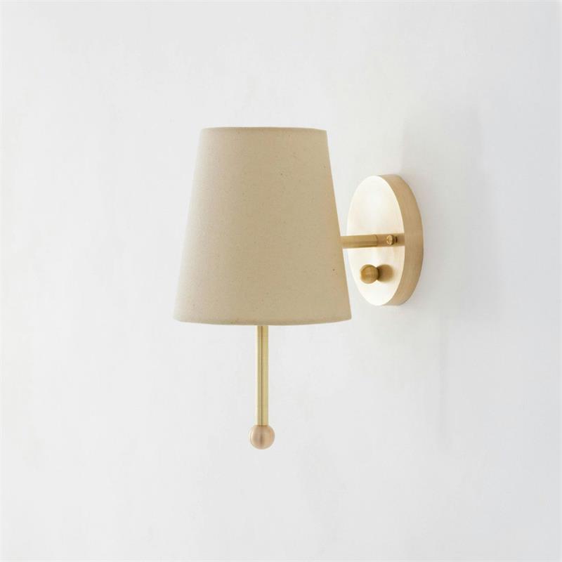 Detailed shot of the brass mounting plate and arm of the wall lamp.