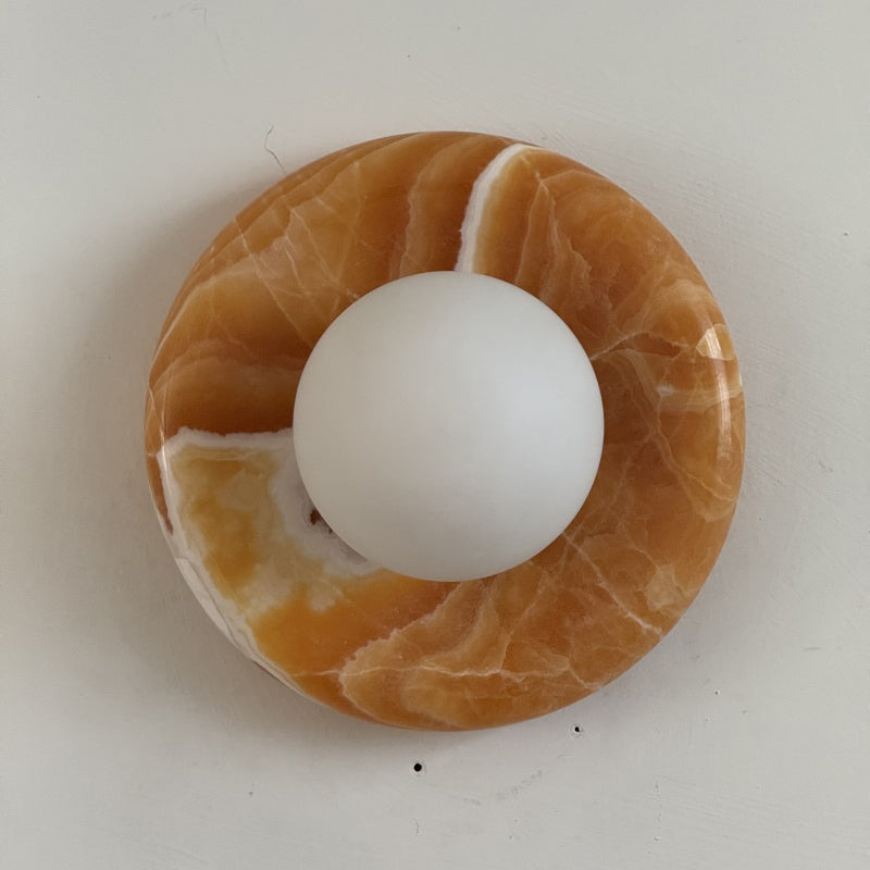 Orli Yellow Onyx Sconce against a dark-colored wall for contrast.