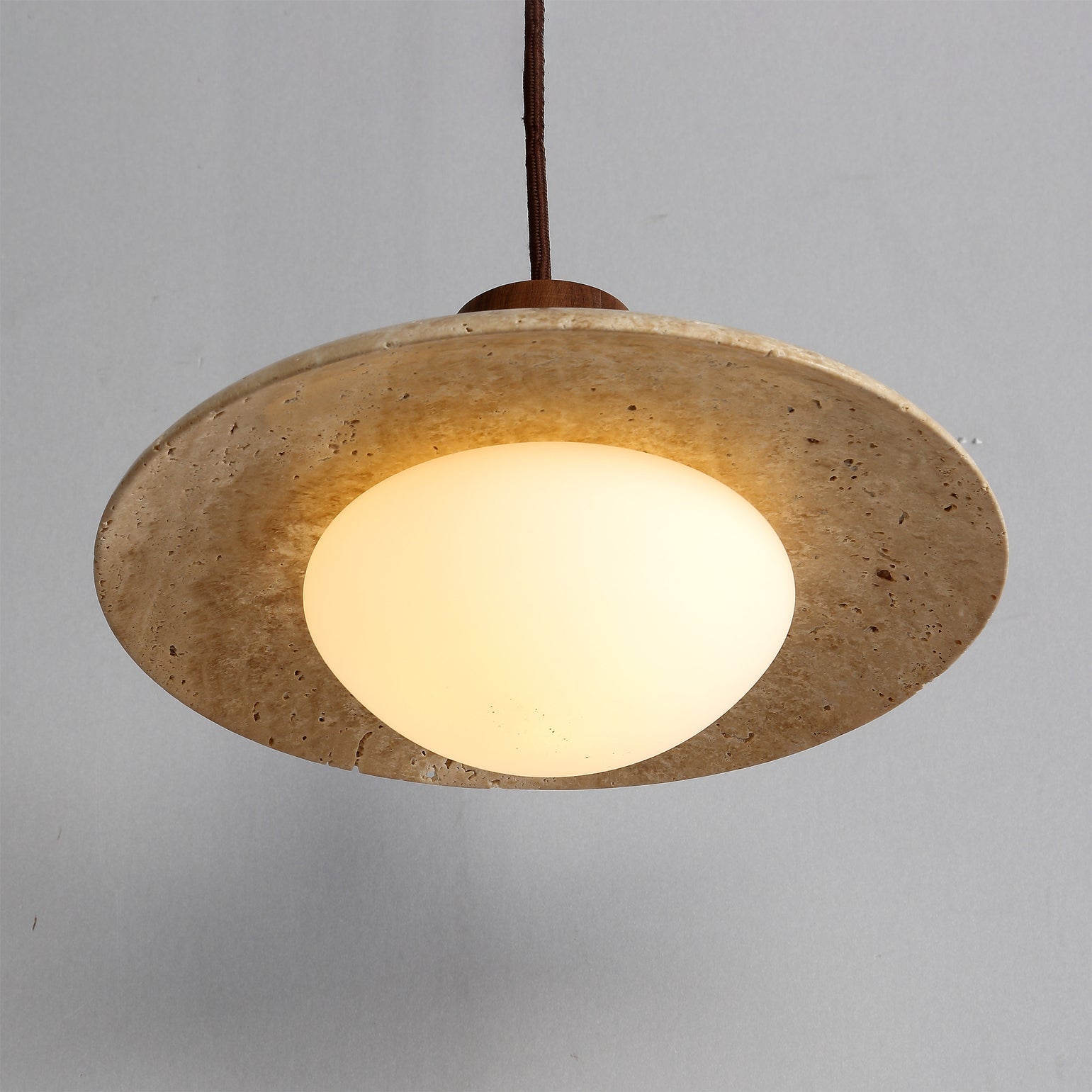 A lifestyle shot of the travertine pendant lamp illuminating a corner of a room.