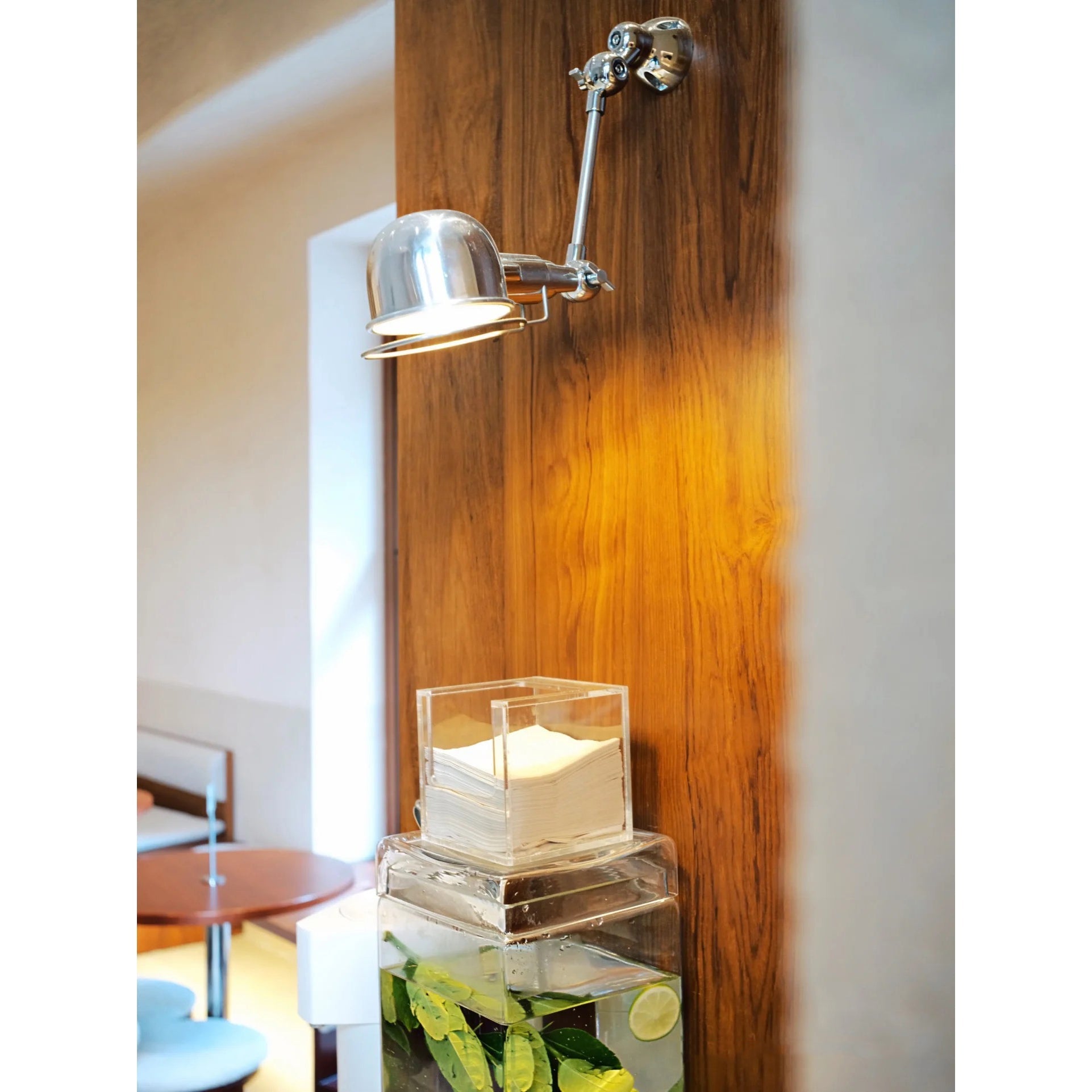 The silver Jielde wall lamp turned on, casting a warm glow.