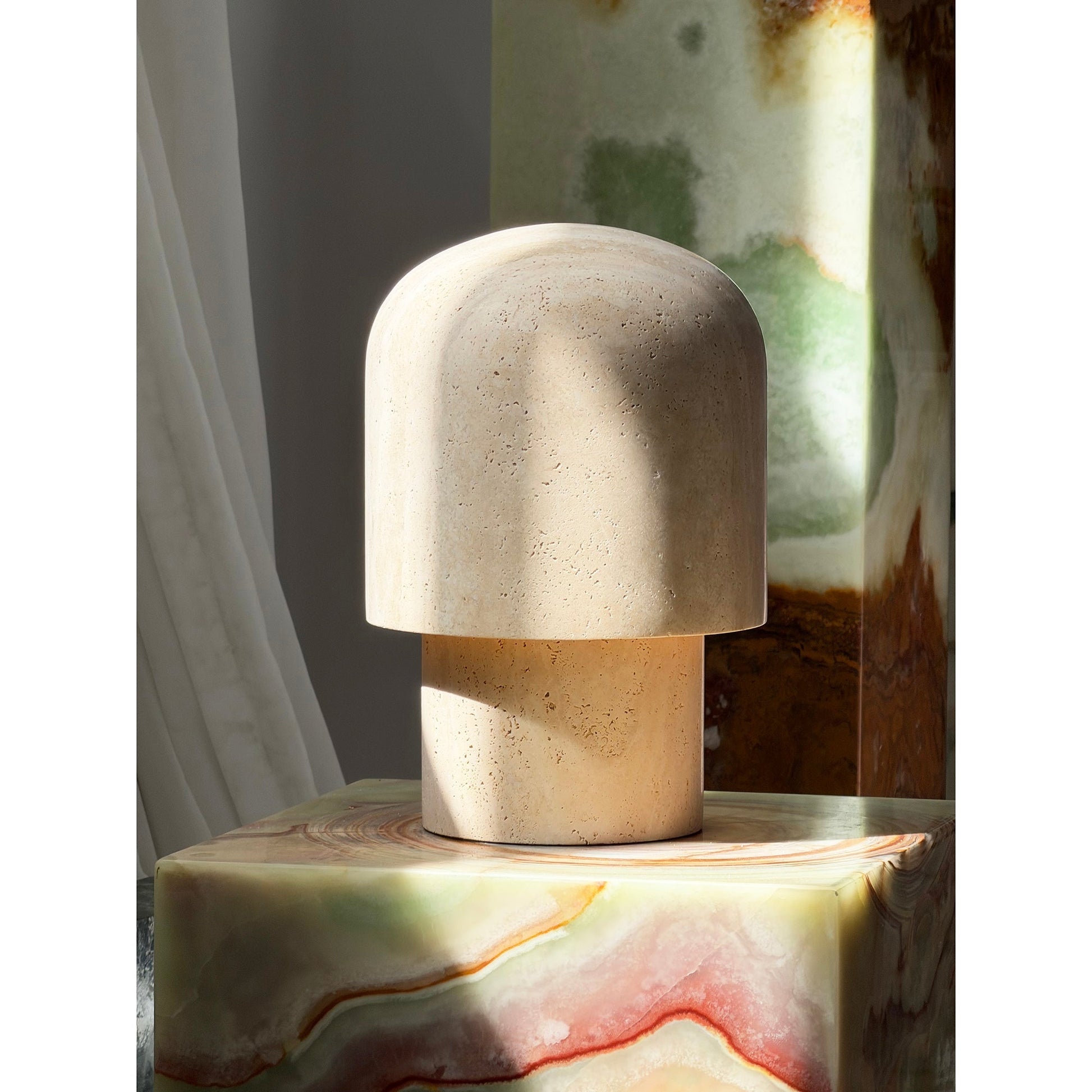 The Kennett Travertine Table Lamp in a bedroom setting on a nightstand.