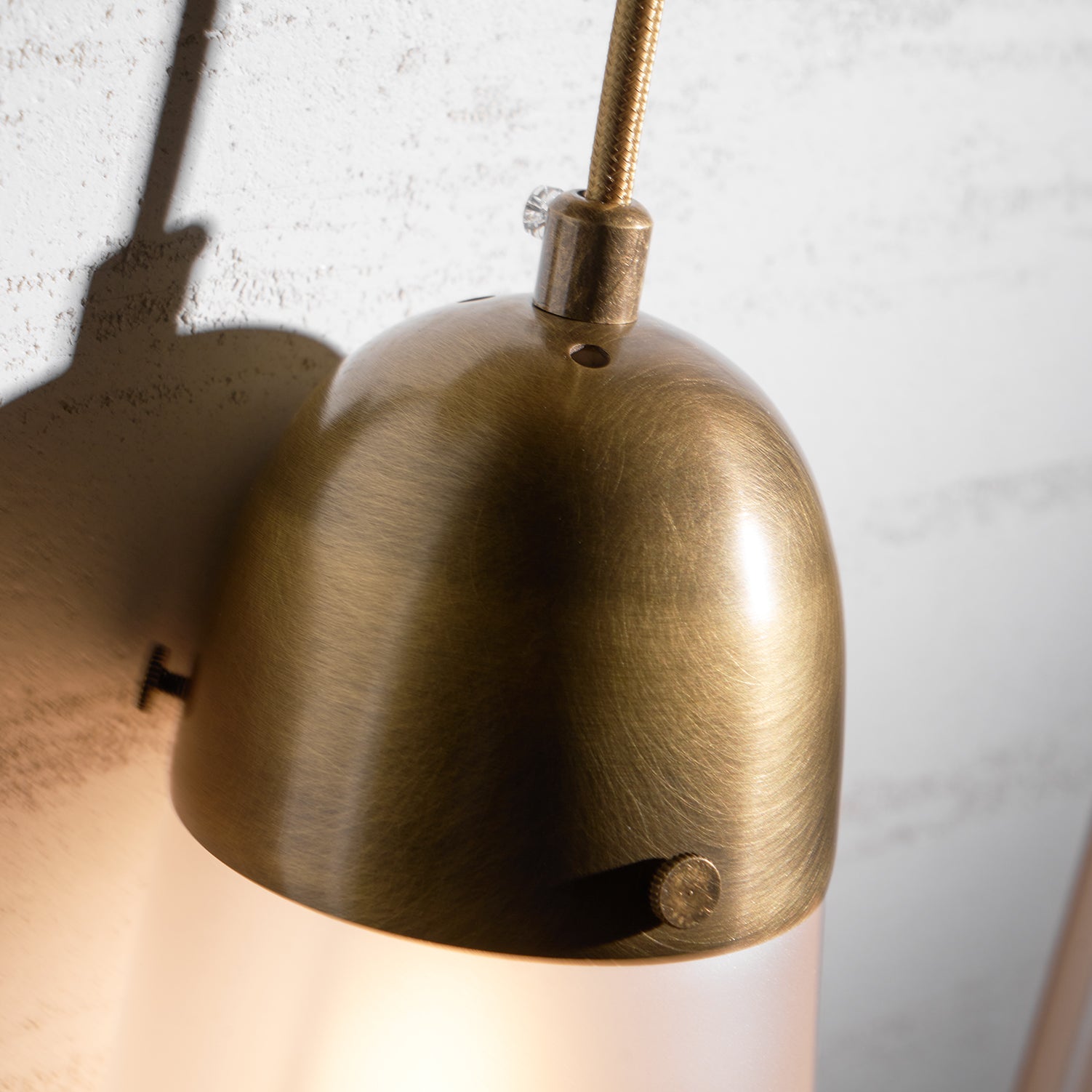 Lariat Wall Lamp, white finish, against a textured wallpaper.