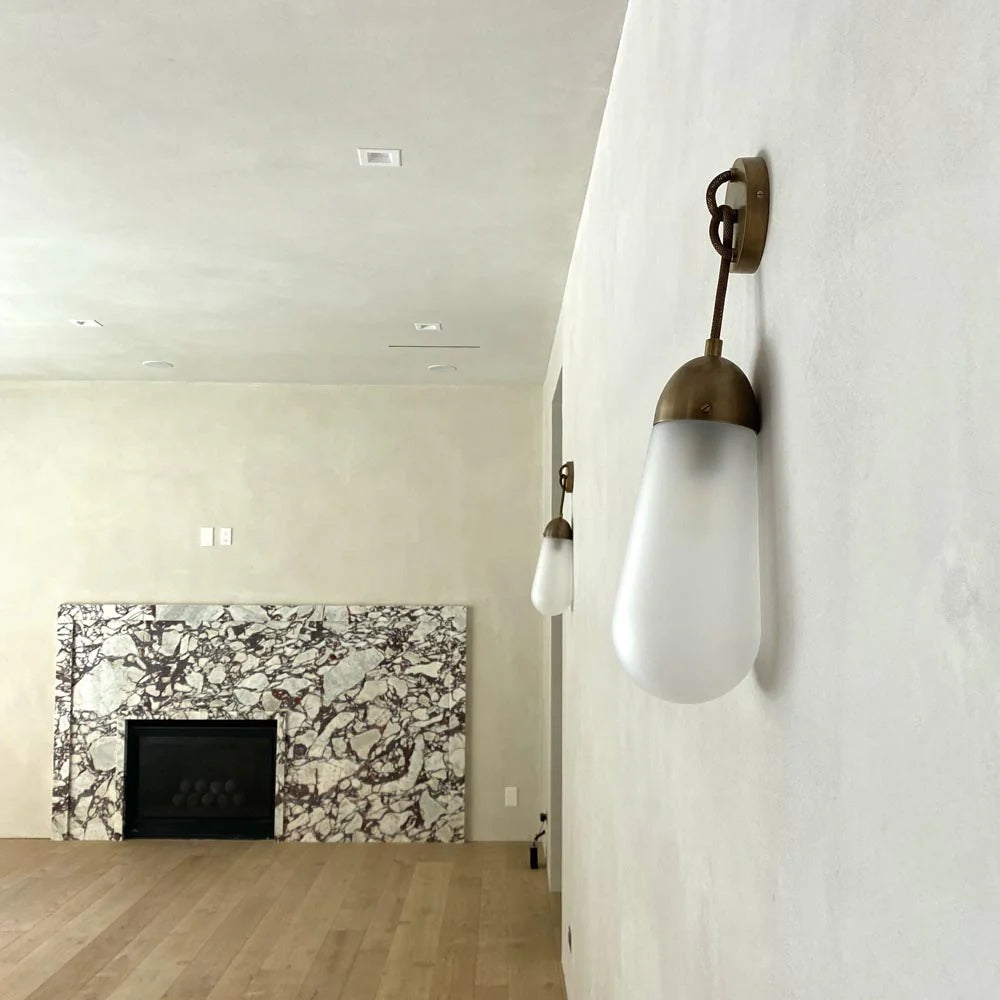 Close-up of the Lariat Wall Lamp's glass shade and brass body.
